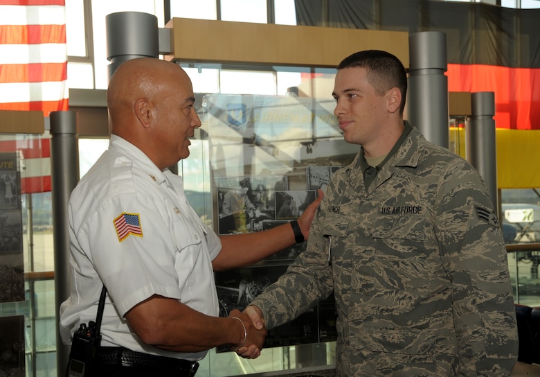 Tony Rabonza, 86th Civil Engineer Squadron Fire Emergency Services chief, presents Senior Airman Corey French, 721st Aerial Port Squadron passenger service agent, with the 86th CES Fire Department coin at Ramstein Air Base, Germany, Oct. 4, 2016. Rabonza coined French for successfully extinguishing a fire in base housing before in caused serious damage. (U.S. Air Force photo by Staff Sgt. Timothy Moore)