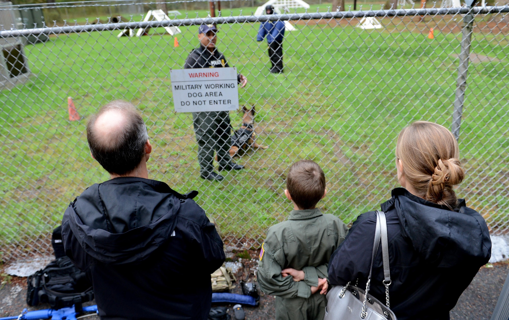 Ben Lambertson (middle) and his parents Paul (left) and Michelle (right), watch a Military Working Dog demo during his Pilot for a Day visit Oct. 7, 2016 at Joint Base Lewis-McChord, Wash. While at the MWD demo, Ben and his family had a chance to interact with the canines, and observe working dogs doing some obedience training and bite work. (U.S. Air Force photo/Senior Airman Divine Cox)