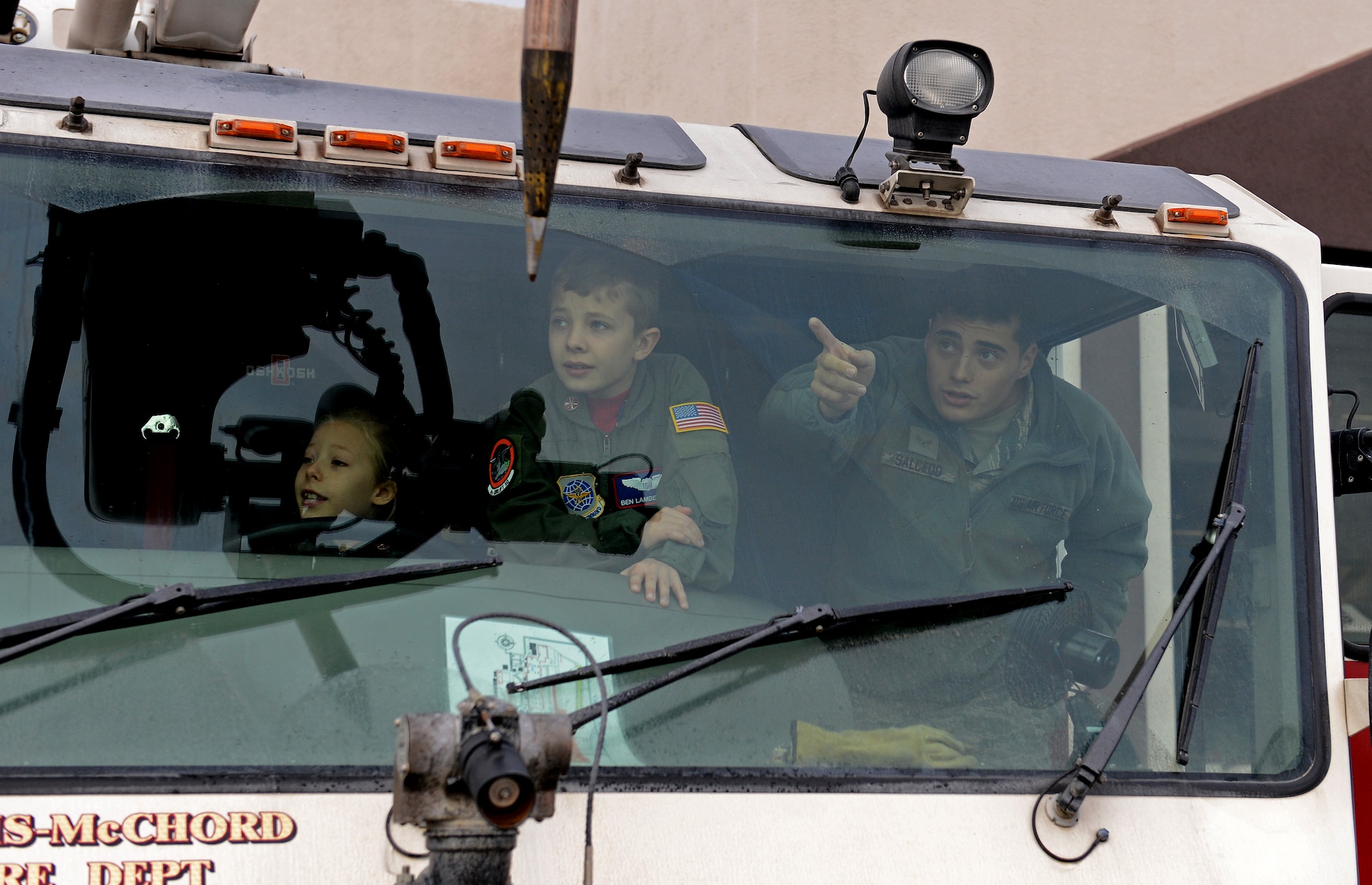 Ben Lambertson (middle) and his sister Maddie (left), look out over the flight line from inside a fire truck demo during his Pilot for a Day visit Oct. 7, 2016 at Joint Base Lewis-McChord, Wash. Ben was honored as Pilot for a Day and was able to tour multiple organizations on McChord Field. (U.S. Air Force photo/Senior Airman Divine Cox)