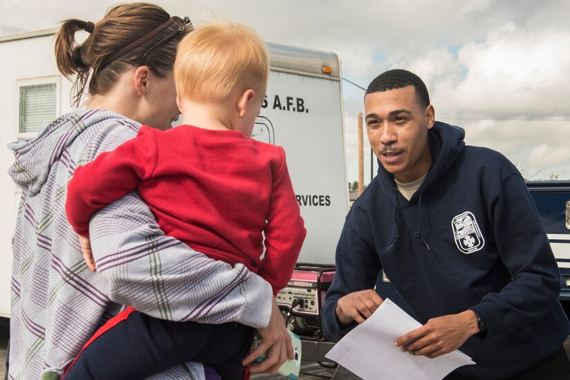 Senior Airman Tevin Charles, 11th Civil Engineer Squadron firefighter, hands out information packets to participants of a Fire Prevention Week event at Joint Base Andrews, Md., Oct. 12, 2016. Children were given coloring books, firefighter helmets and pamphlets to foster their understanding of fire safety and emergency procedures. (U.S. Air Force Photo by Senior Airman Jordyn Fetter)