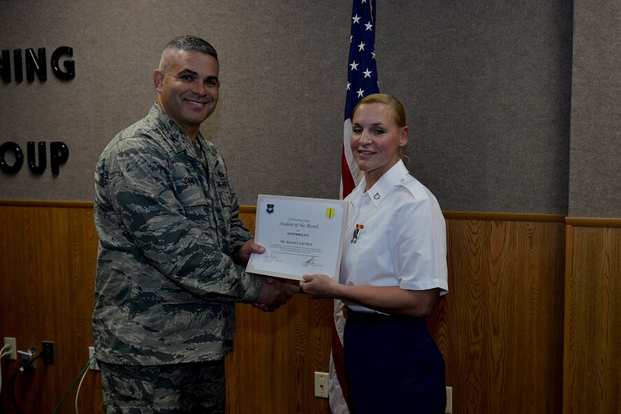 U.S. Air Force Col. Alex Ganster, 17th Training Group Commander, presents the 312th Training Squadron Student of the Month award for September 2016 to U.S. Army Pfc. Regina Giudice at Brandenburg Hall on Goodfellow Air Force Base, Texas, Oct. 7, 2016. (U.S. Air Force photo by Airman 1st Class Randall Moose/Released)