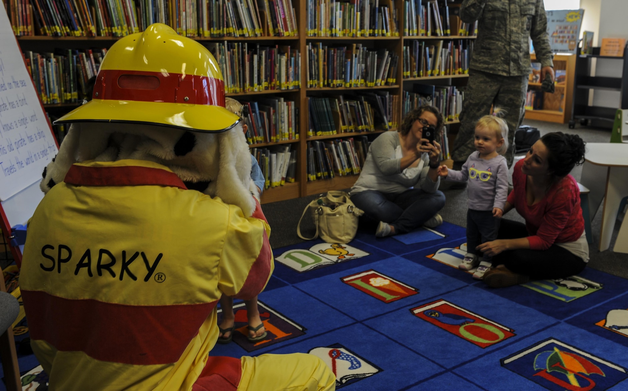 “Sparky the Fire Dog,” the National Fire Prevention Association mascot, plays peek-a-boo with children after story time at the library on Hurlburt Field, Fla., Oct. 13, 2016. The 1st Special Operations Civil Engineer Squadron Fire Department and Sparky visited Child Development Centers, the base library and other locations throughout the week to educate and raise awareness about fire prevention. (U.S. Air Force photo by Airman 1st Class Isaac O. Guest IV)