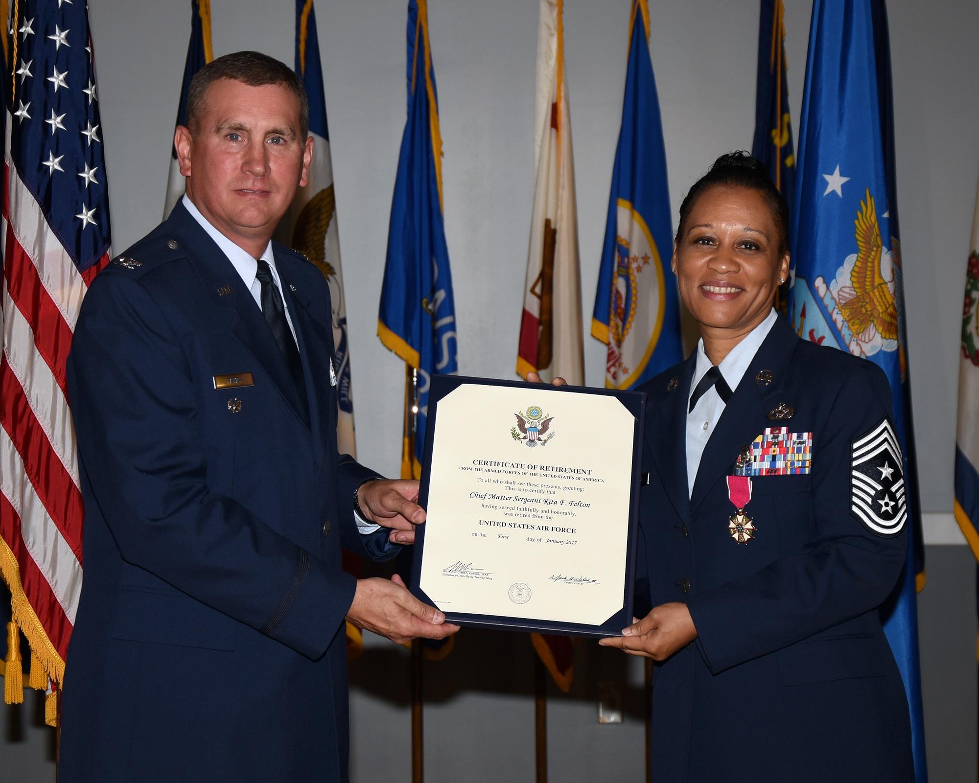 Col. James Fisher, 14th Flying Training Wing Vice Commander, hands Chief Master Sgt. Rita Felton, 14th Flying Training Wing Command Chief, her Certificate of Retirement Oct. 7 at Columbus Air Force Base, Mississippi. Felton served in the military for 30 years before joining her husband Derk Felton in retirement. (U.S. Air Force photo by Sharon Ybarra)