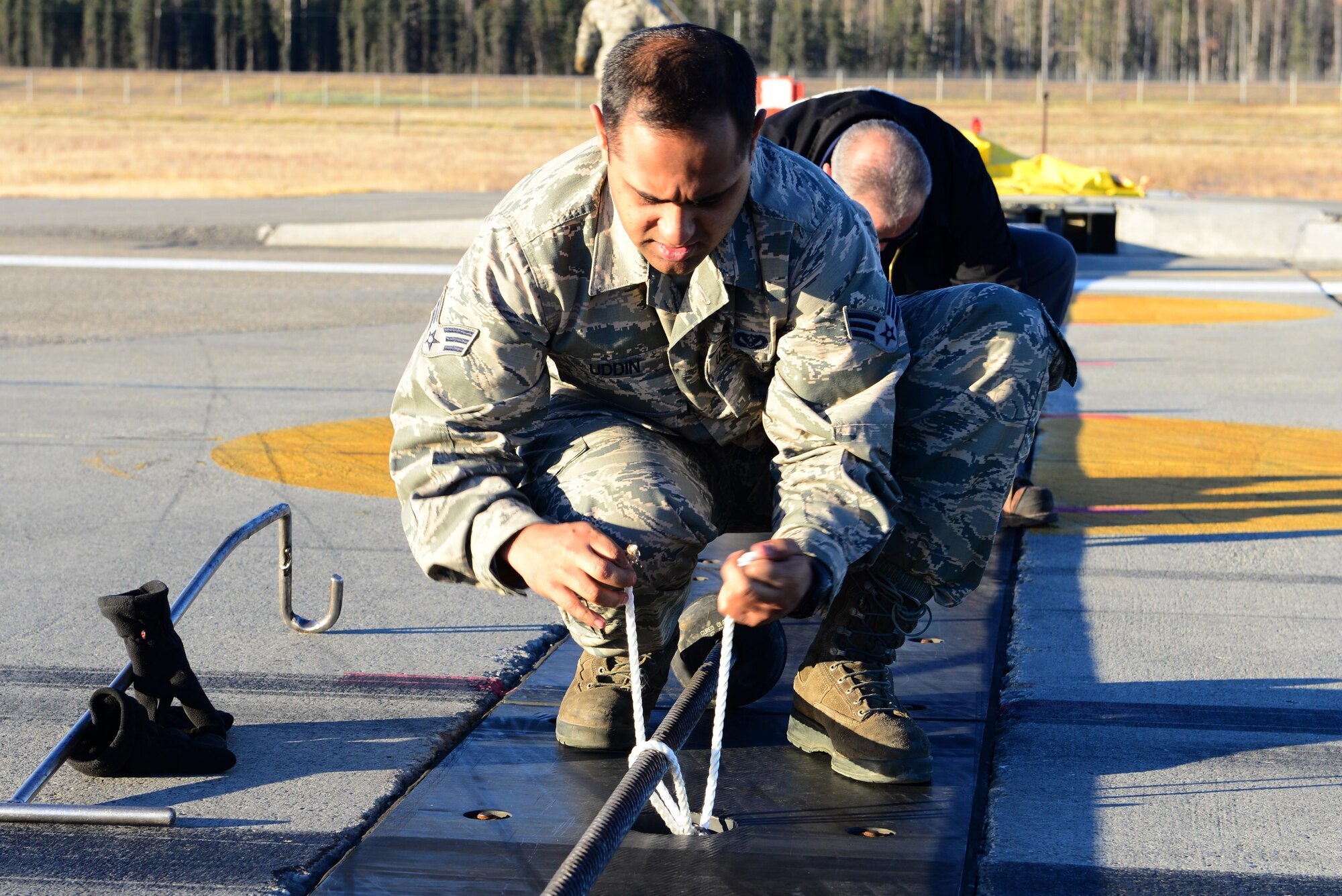 U.S. Air Force Senior Airman Arbab Uddin, a 354th Civil Engineer Squadron power production technician, ties down a barrier Oct. 12, 2016, at Eielson Air Force Base, Alaska. RED FLAG-Alaska 17-1 is in its third day and flying operations would slow if Uddin and the rest of the power production Airmen weren’t efficient in their job. (U.S. Air Force photo by Airman 1st Class Cassandra Whitman)