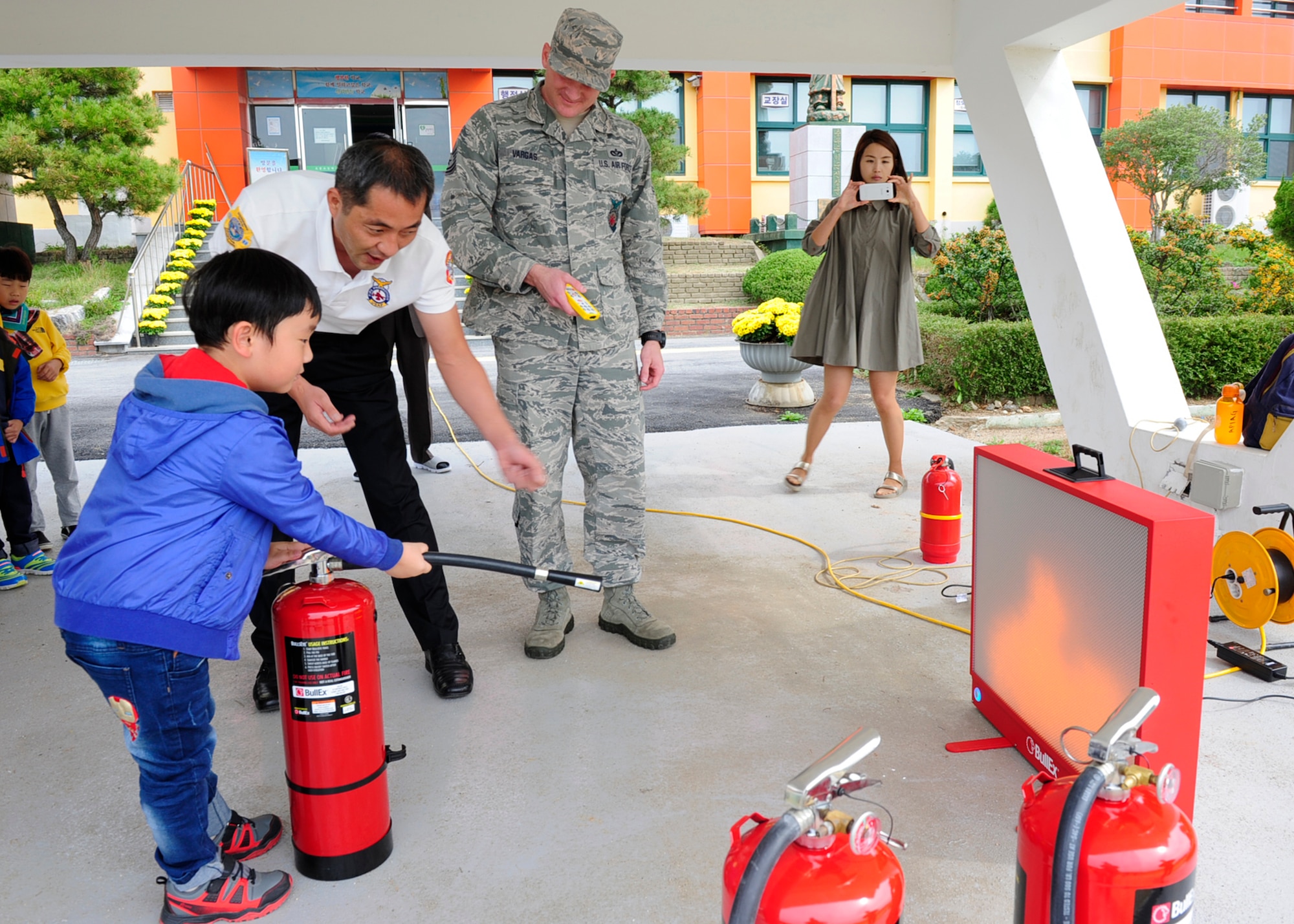 Firefighters from the 8th Civil Engineer Squadron, teach a student how to extinguish a fire while visiting Okbong Elementary School, Gunsan, Republic of Korea, Oct. 13, 2016. The visit was part of the 2016 Fire Prevention Week campaign, which will run from Oct. 9-15. This year’s theme is “Don’t Wait – Check the Date! Replace Smoke Alarms Every 10 Years.” (U.S. Air Force photo by Staff Sgt. Chelsea Browning/Released)