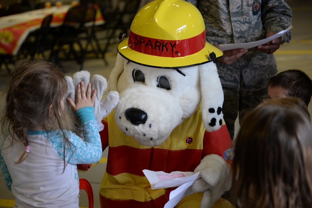 Sparky the Firedog gives a high five to a child Oct. 10 during Fire Prevention Week at Columbus Air Force Base, Mississippi. The children in attendance celebrated Sparky’s 94th birthday at the party with games and more. (U.S. Air Force photo/Airman 1st Class John Day)
