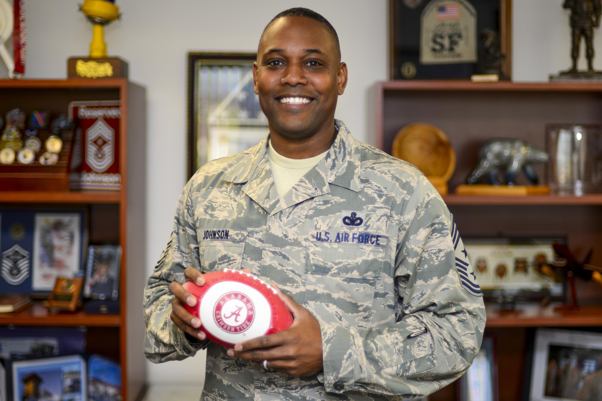 Chief Master Sgt. Anthony Johnson, 7th Air Force command chief, poses with a University of Alabama football in his office at Osan Air Base, Republic of Korea, Oct. 13, 2016. Johnson was recently nominated to be the next Pacific Air Forces command chief master sergeant. (U.S. Air Force photo by Senior Airman Victor J. Caputo)