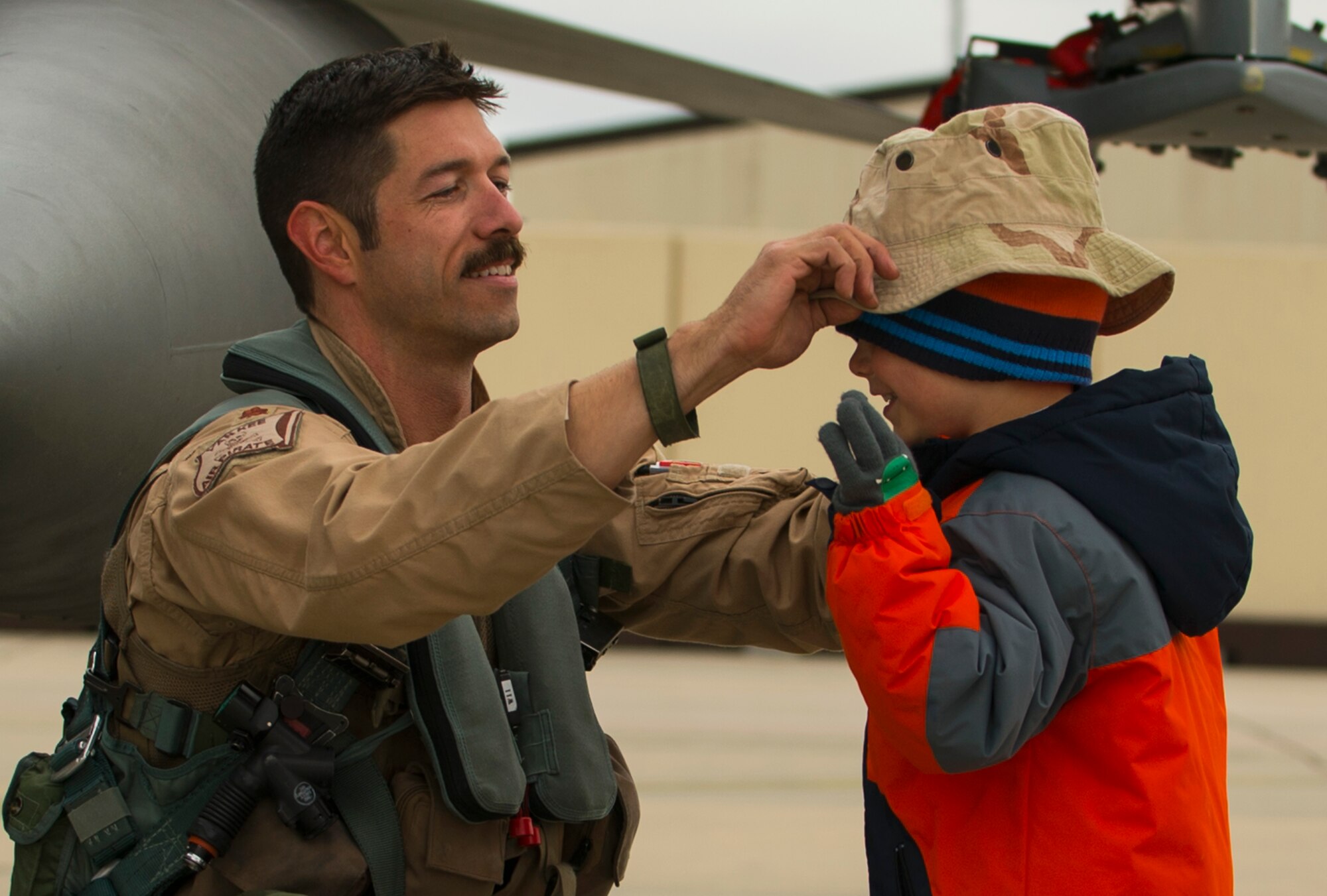 An Airman assigned to the 480th Expeditionary Fighter Squadron places a hat on his son’s head on the flightline at Spangdahlem Air Base, Germany, Oct. 6, 2016. Members of the 480th EFS and supporting agencies deployed to support Operation Inherent Resolve. (U.S. Air Force photo by Senior Airman Dawn M. Weber)