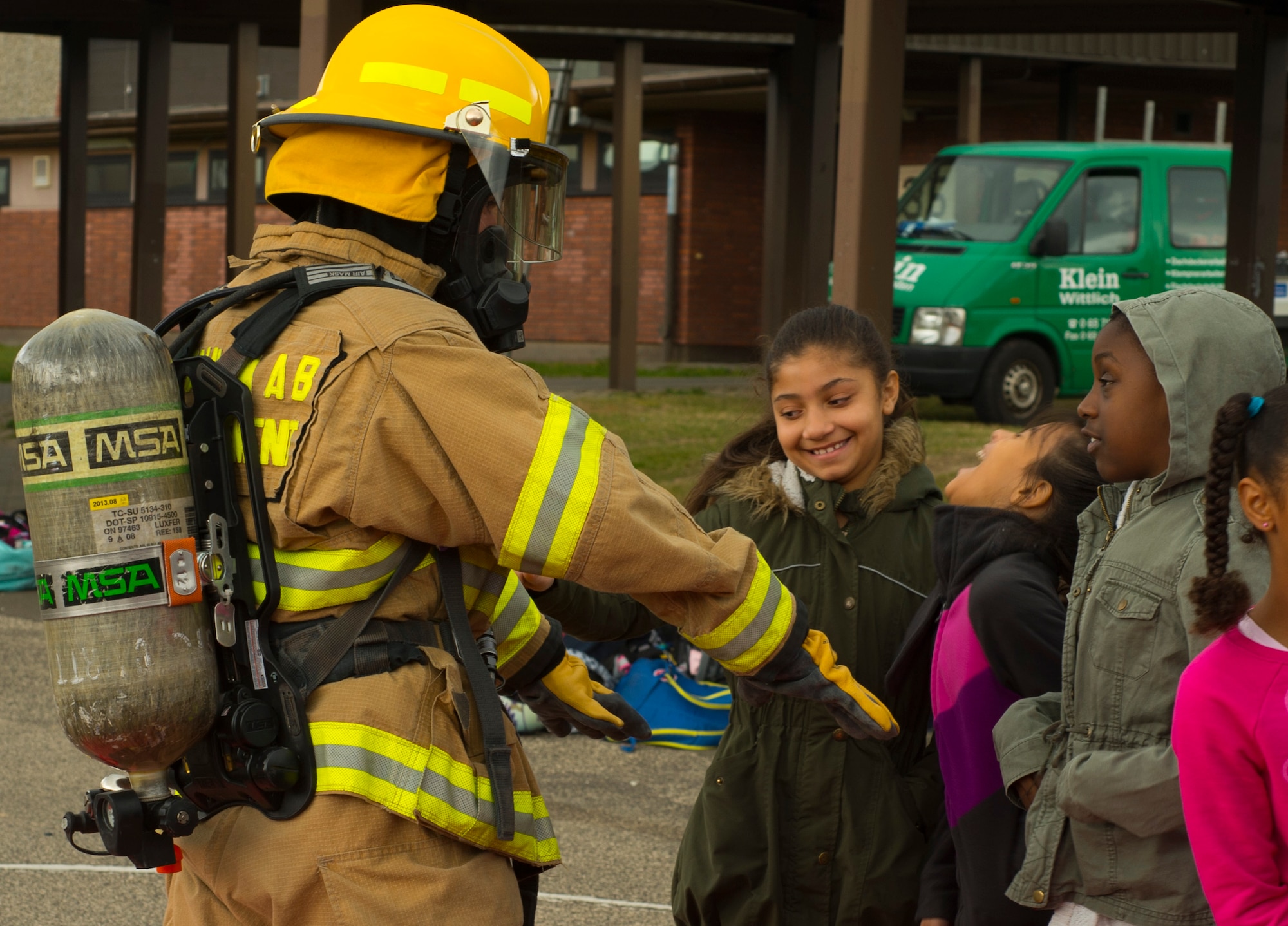 U.S. Air Force Airman Robert Keowalski, 52nd Civil Engineer Squadron firefighter, shows Spangdahlem Elementary School students firefighter equipment while visiting SES on Spangdahlem Air Base, Germany, Oct. 12, 2016. The additional gear a firefighter wears weighs approximately 75 pounds. The firefighters demonstrated the importance of fire safety to students in observance of Fire Prevention Week. (U.S. Air Force photo by Senior Airman Dawn M. Weber)