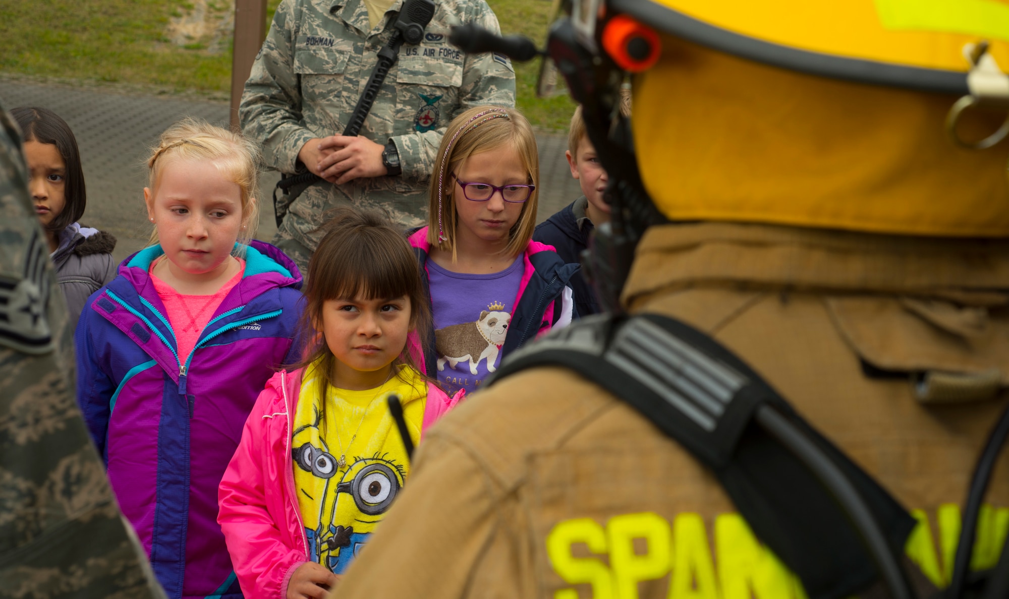 Spangdahelm Elementary School students listen as 52nd Civil Engineer Squadron firefighters teach them about firefighter equipment while visiting SES on Spangdahlem Air Base, Germany,  Oct. 12, 2016. The additional gear a firefighter wears weighs approximately 75 pounds. The firefighters demonstrated the importance of fire safety to the students in observance of Fire Prevention Week. (U.S. Air Force photo by Senior Airman Dawn M. Weber)