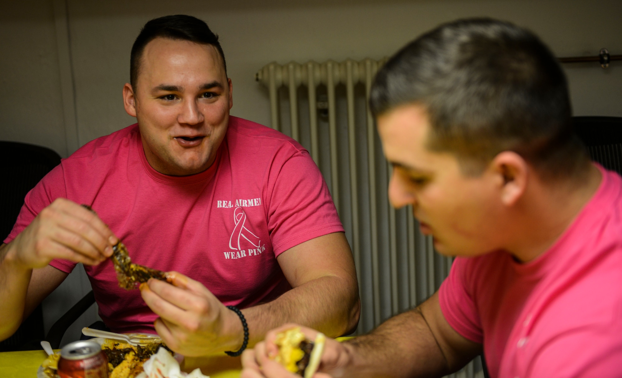 Airman 1st Class Clayton Hardie, left, and Senior Airman Drake Futch, both 86th Dental Squadron dental technicians, wear pink morale shirts during a unit potluck on Ramstein Air Base, Germany, Oct. 7, 2016. The potluck was held on the first day the unit Airmen wore the morale shirts in observance of Breast Cancer Awareness Month. (U.S. Air Force photo by Airman 1st Class Joshua Magbanua)