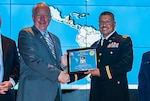 James McClaugherty, DLA Land and Maritime acting commander (left) presents Maj. Claudio Garcia-Castro with a framed program from DLA Land and Maritime's National Hispanic Heritage Month program. Garcia-Castro shared his story of overcoming cultural obstacles and becoming a commissioned officer in the U.S. Army.  