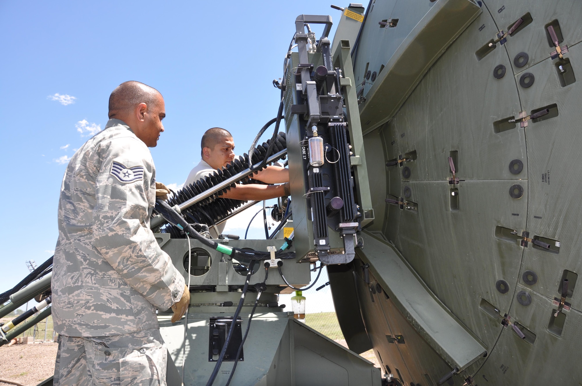 Staff Sgt. Antony Pottakkal (left) and Tech. Sgt. Raul Pasillas change a satellite feed horn on a quad band large aperture antenna in preparation for a new signal verification. (U.S. Air Force photo/Maj. Jessica D'Ambrosio)