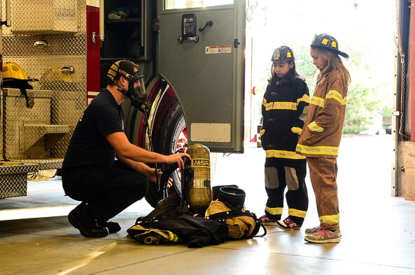 Reagan Marcotte, 775th Civil Engineer Squadron firefighter, shows Hill Field Elementary School students Chantel Bailey, center, and Shea Opdahl firefighting equipment Oct. 13 at Hill Air Force Base. The students got to spend the day with Hill Air Force Base Fire Department personnel after winning an essay contest at their school. (U.S. Air Force photo by R. Nial Bradshaw)