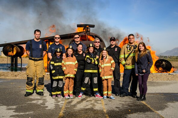 Hill Air Force Base firefighters pose with four Hill Field Elementary School students Oct. 13 at the base. Students, from the left, Chantel Bailey, Shea Opdahl, Jade Langley and Sarah Cunieo spent the day as firefighters for winning an essay contest. (U.S. Air Force photo by R. Nial Bradshaw)