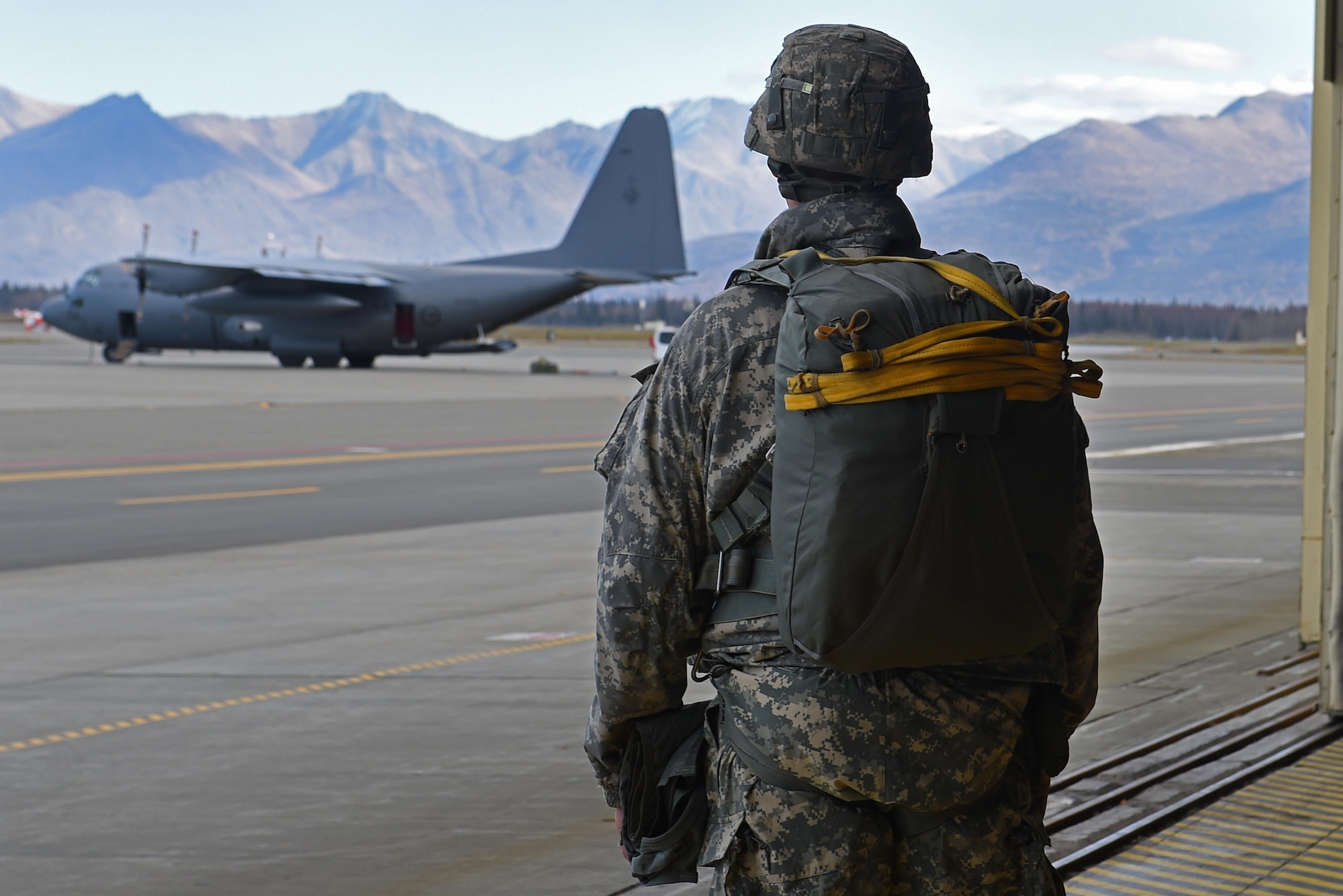 A paratrooper with the 4th Infantry Brigade Combat Team (Airborne), 25th Infantry Division, U.S. Army Alaska, observes a Royal New Zealand Air Force C-130 Hercules before boarding for a jump during Red-Flag Alaska 17-1 at Joint Base Elmendorf-Richardson, Alaska, Oct. 12, 2016. Red-Flag Alaska 17-1 provides joint offensive counter-air, interdiction, close air support, and large force employment training in a simulated combat environment. 