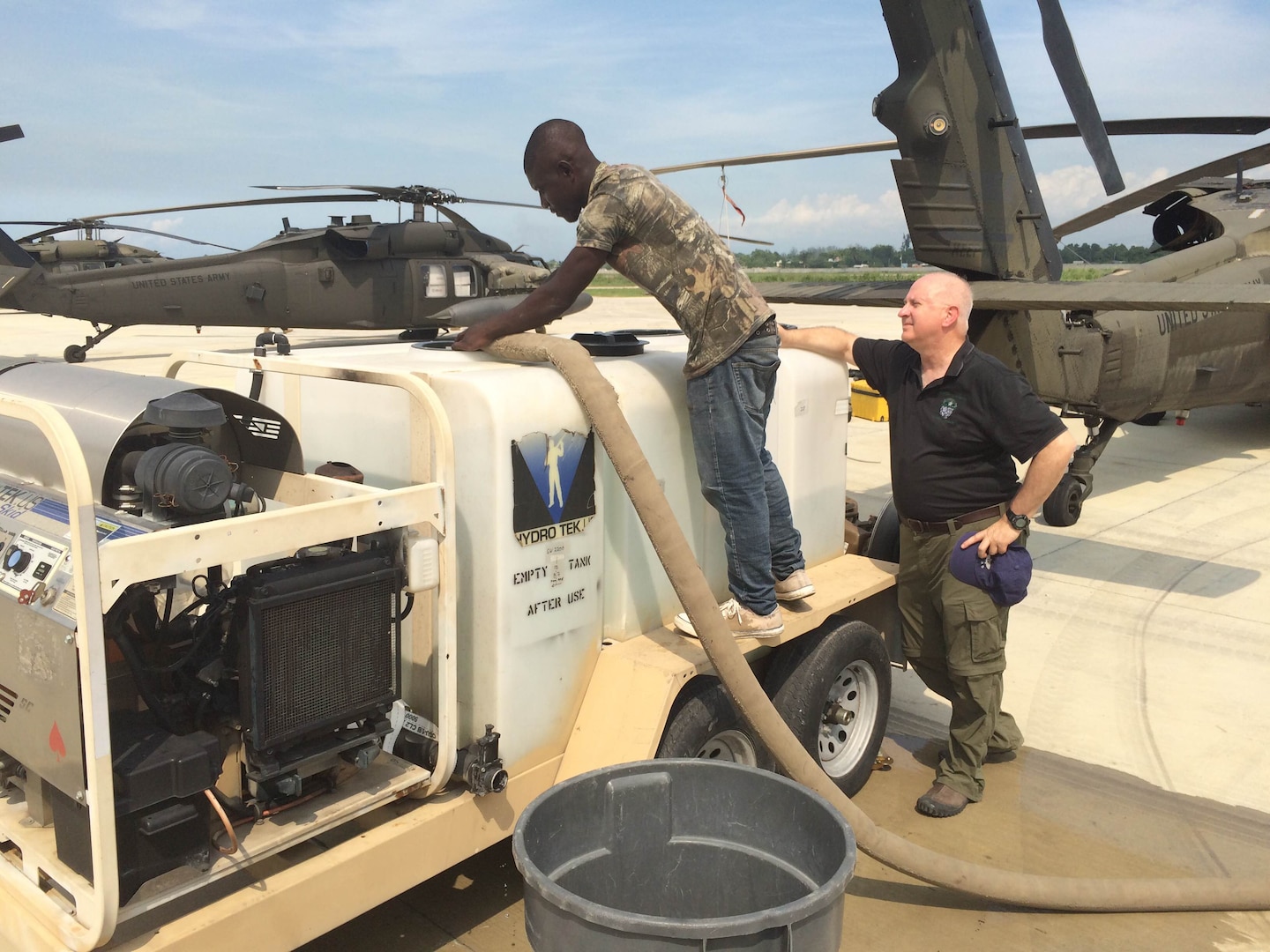 Craig Hill (right), an expeditionary contracting officer for DLA’s Joint Contingency Acquisition Support Office, observes a DLA Troop Support contractor fill an aircraft wash tank with non-potable water at Port-au-Prince, Haiti, October 2016. This practice conserved potable water for human consumption.