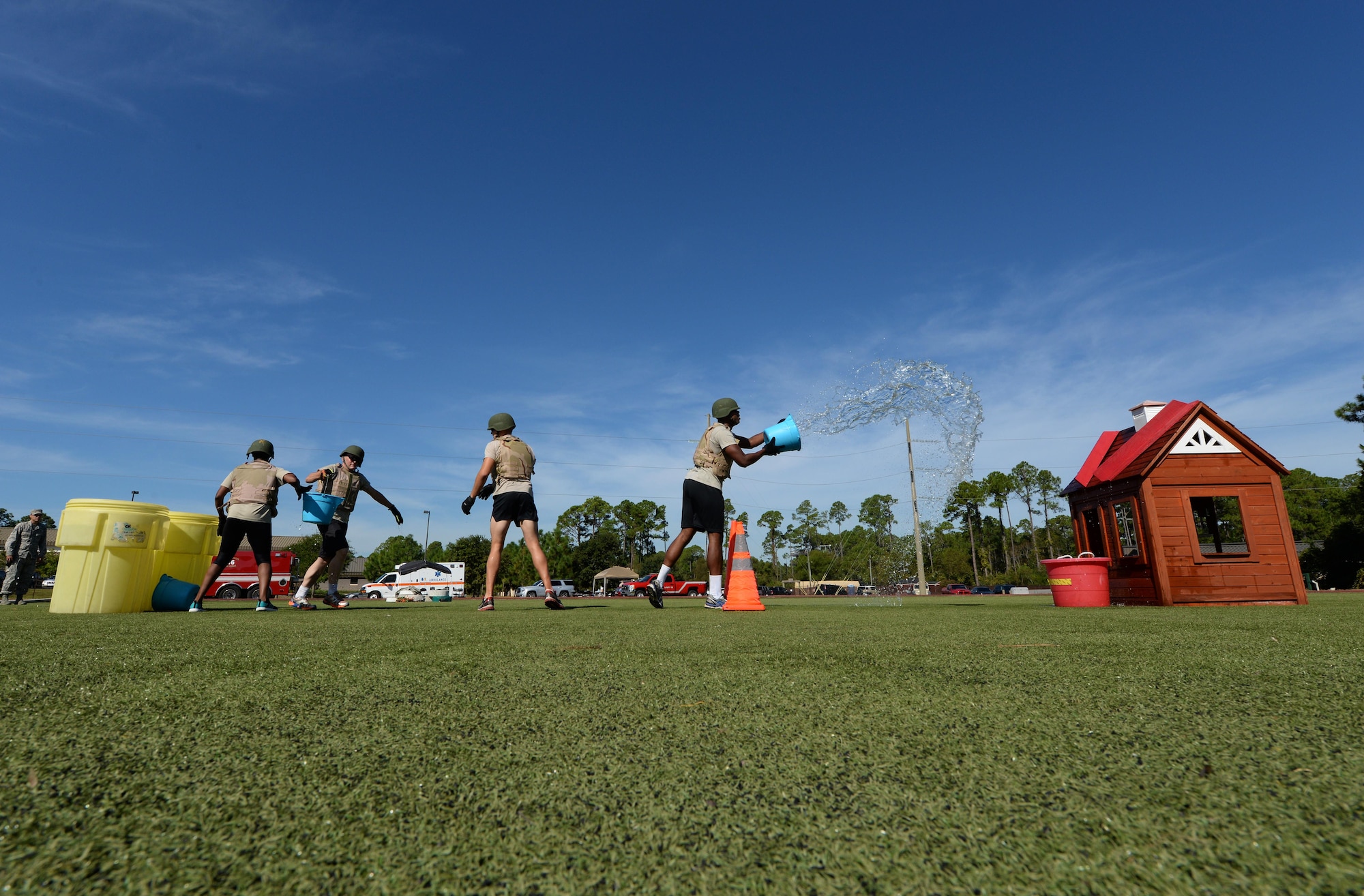 A team of Air Commandos work together to pitch water onto a toy house during the Fire Prevention Week fire muster challenge at Hurlburt Field, Fla., Oct. 14, 2016. This event simulated how fire fighters train to ensure they are ready to react to any emergency anytime, any place. (U.S. Air Force photo by Senior Airman Andrea Posey)