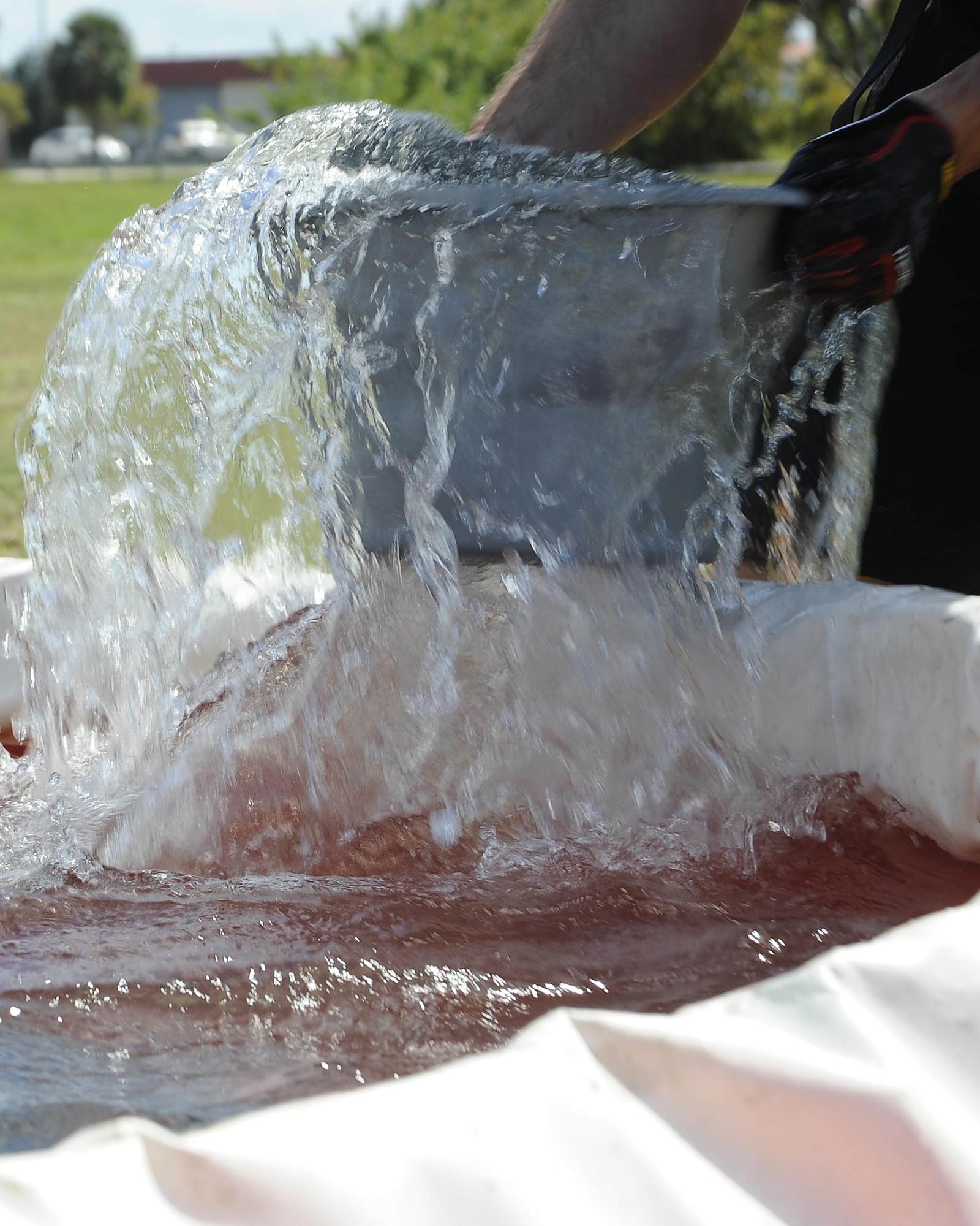 A participant fills a bucket with water at the bucket brigade station during the MacDill’s Inaugural Firefighter’s Challenge at MacDill Air Force Base, Fla., Oct. 14, 2016. During the bucket brigade station, teams used buckets to fill a container to the designated level with water in order to complete the challenge. (U.S. Air Force photo by Airman 1st Class Mariette Adams)