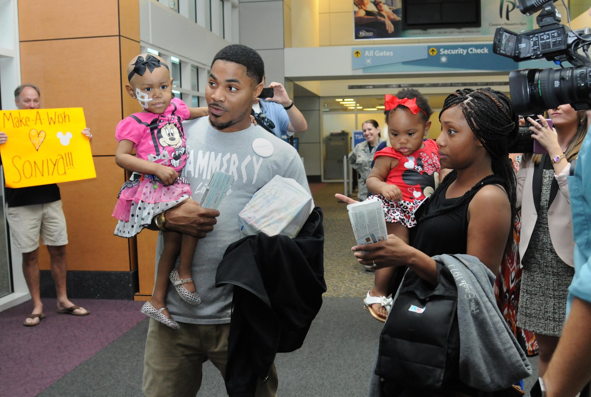 Staff Sgt. Devanie Rainey, 81st Force Support Squadron customer support supervisor, and her family are greeted as they arrive at Gulfport-Biloxi International Airport Oct. 14, 2016, Gulfport, Miss. The Make-A-Wish Foundation flew the Rainey family to Disney World after their daughter, Saniya, was diagnosed with germ cell tumors. Keesler personnel and members from the local community gathered to help send them off. (U.S. Air Force photo by Kemberly Groue/Released)