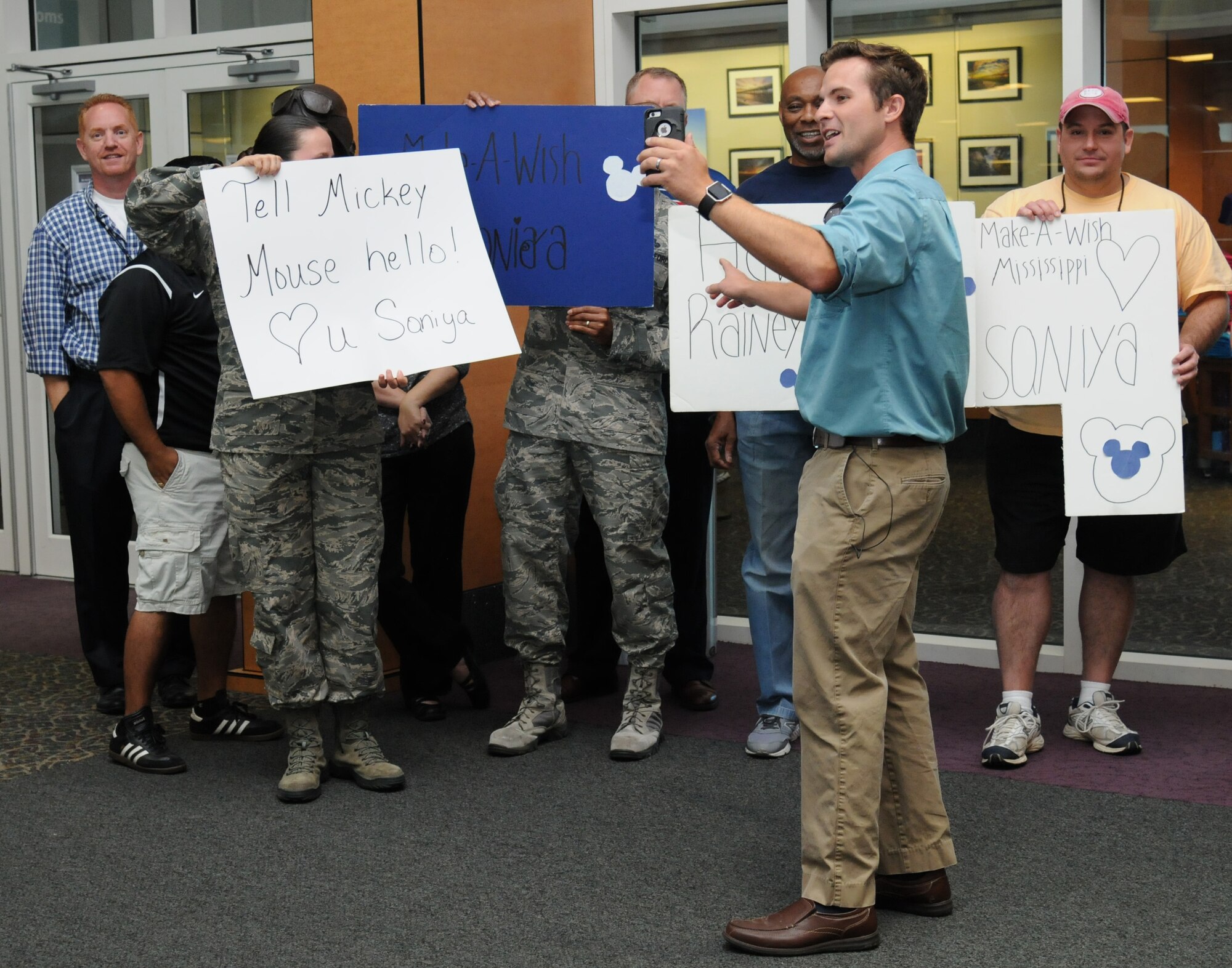 Jonathan Brannan, WLOX reporter, captures a live video stream of the 81st Force Support Squadron and the local community members showing their support for Staff Sgt. Devanie Rainey, 81st FSS customer support supervisor, and her family, upon their arrival at the Gulfport-Biloxi International Airport Oct. 14, 2016, Gulfport, Miss. The Make-A-Wish Foundation flew the Rainey family to Disney World after their daughter, Saniya, was diagnosed with germ cell tumors. (U.S. Air Force photo by Kemberly Groue/Released)