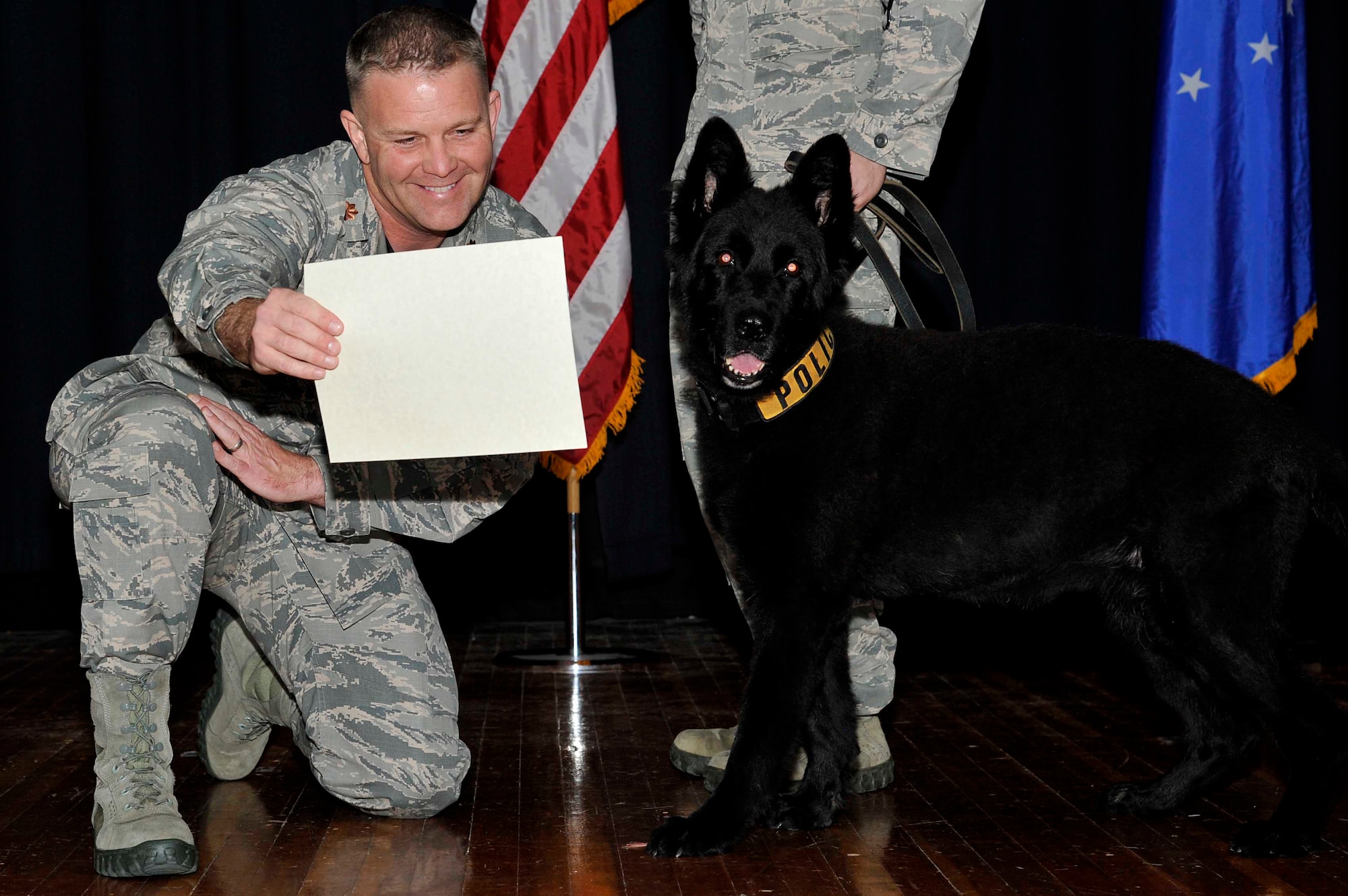 Maj. John Farmer, 22nd Security Forces Squadron commander, presents Djule, a recently retired military working dog, with a certificate of meritorious service during her retirement ceremony Oct. 14, 2016, at McConnell Air Force Base, Kan. Djule went through 1,846 hours of detection training and conducted 1,630 detector sweeps in her career. (U.S. Air Force photo/Airman Erin McClellan)
