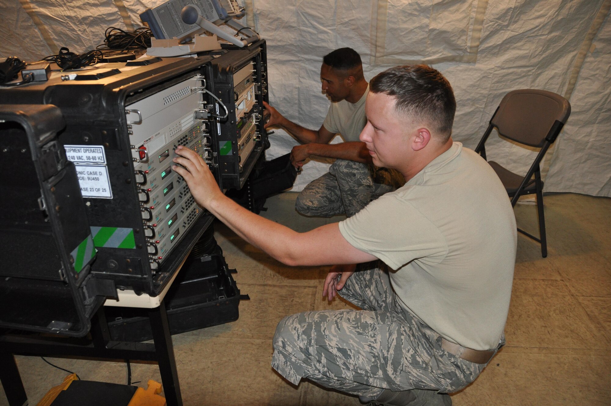 Senior Airman Alexander Zeiler (front) and Staff Sgt. Poitier Wright program the direction of a dish in order to track satellites. Zeiler sets up a high-powered amplifier to provide power while Wright sets up the antenna control units which control the direction of the dish and antenna. (U.S. Air Force photo/Maj. Jessica D'Ambrosio)