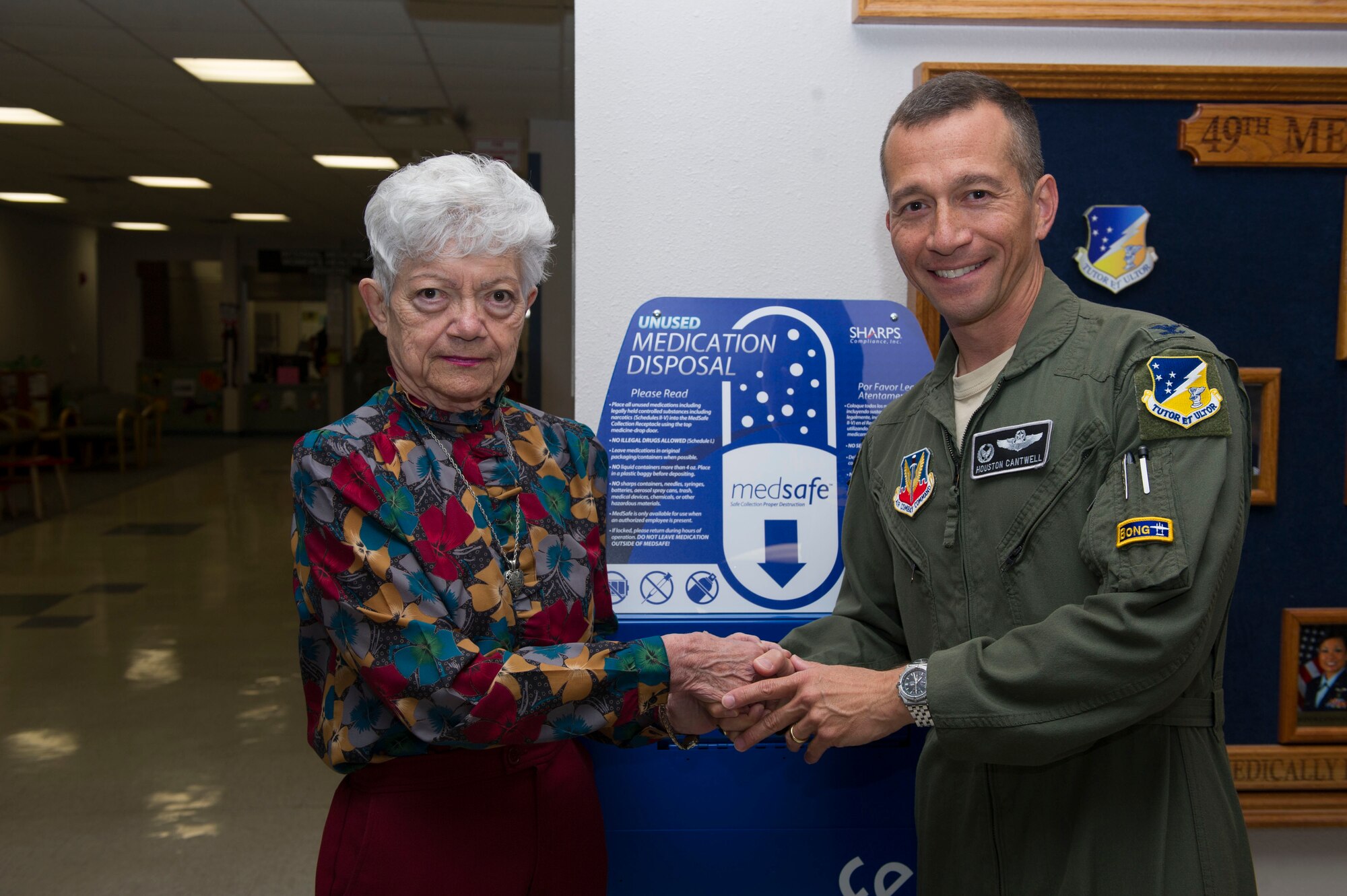 Col. Houston Cantwell, the 49th Wing commander, shakes hands with Matilda Smith, the first person to donate medications as part of the medical group’s ceremony, Oct. 14, 2016. (U.S. Air Force photo by Tech. Sgt. Matthew Rosine.) 