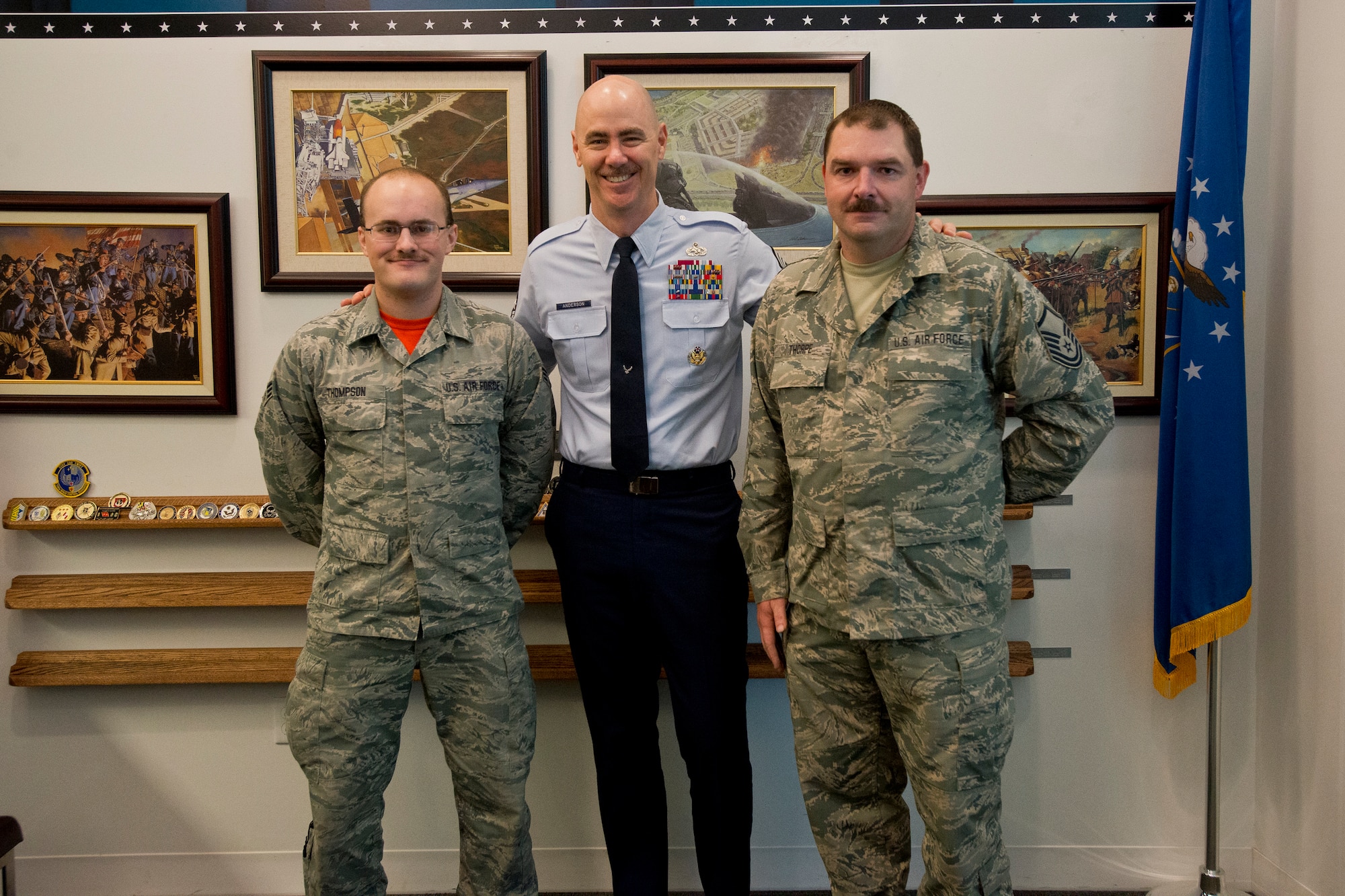 SrA Zachary Thompson, 113th Logistics Readiness Squadron, DC Air National Guard, Command Chief Master Sergeant of the ANG, Ronald C. Anderson, and Master Sgt. Robert Thorpe, ANG Manpower, Personnel and Services Directorate, pose for a photo after Anderson was presented with coin #12 from the Airman to Airman Coin Project, October 14, 2016. Thompson and Thorpe created the coin project as a way for enlisted Airmen to recognize each other for their efforts in the moment, and to spur a culture change to focus on positive actions rather than negative ones. (U.S. Air National Guard photo by Staff Sgt. John E. Hillier)