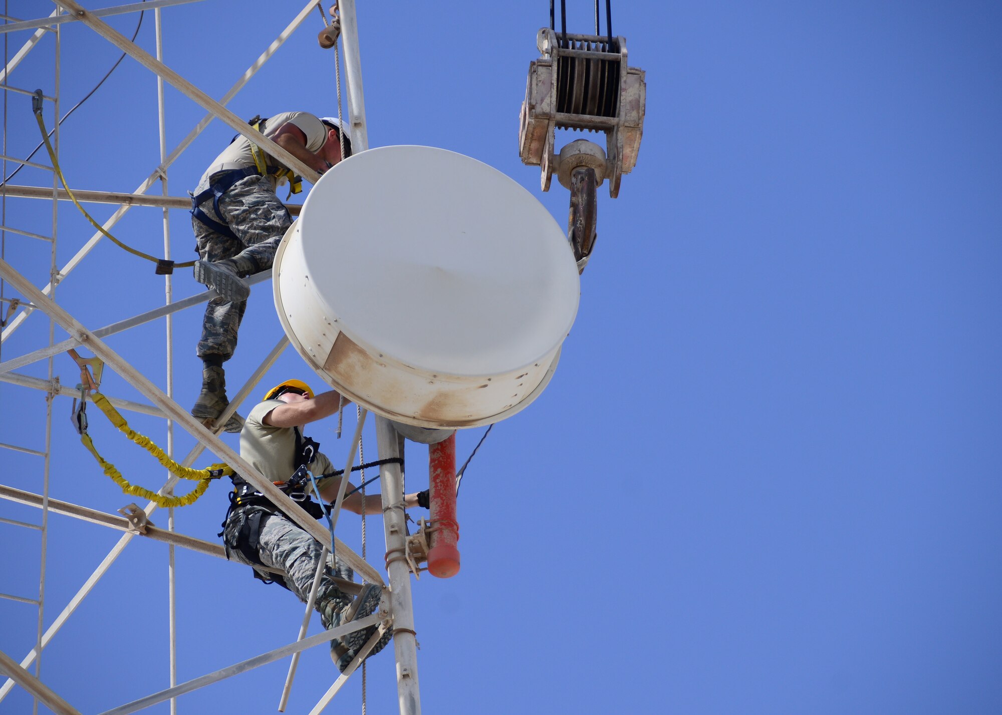 Airmen from the 379th Expeditionary Communications Squadron and 379th Expeditionary Civil Engineer Squadron work together on taking down an inactive microwave dish transmitter from a radio tower Oct. 8, 2016, at Al Udeid Air Base, Qatar. The transmitters weighed up to 200 pounds each and required the use of a Terex RT 780 crane to take down safely. (U.S. Air Force photo/Senior Airman Miles Wilson/Released)