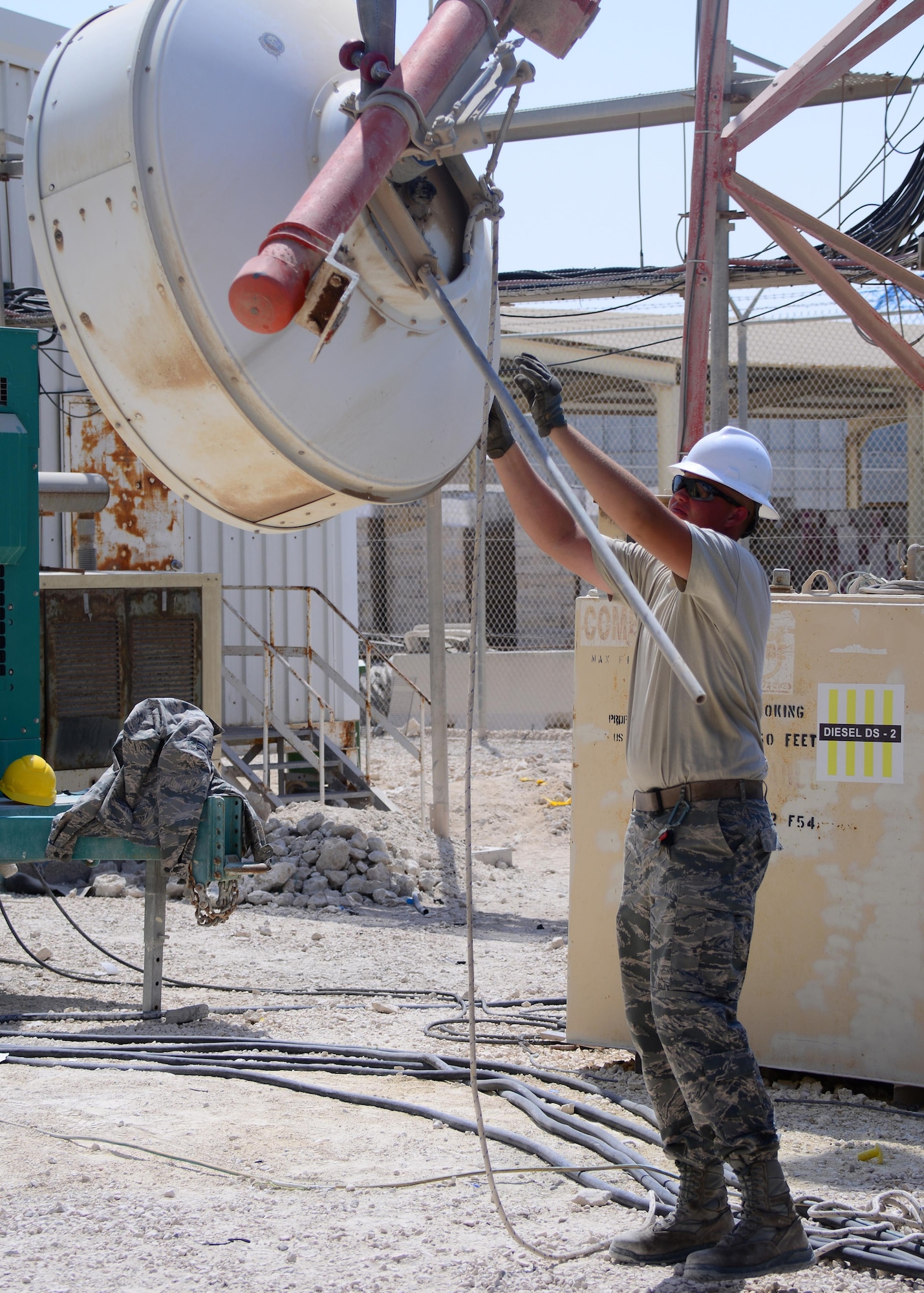 Airman 1st Class Ryan Batt, 379th Expeditionary Civil Engineering Squadron Pavement and Heavy Equipment specialist, guides a microwave transmitter down to the ground after it was removed from a radio tower Oct. 8, 2016, at Al Udeid Air Base, Qatar. The transmitter, along with the metal bar it was mounted on, weighed over 200 pounds and required the use of a Terex RT-780 crane to be removed safely. (U.S. Air Force Photo/Senior Airman Miles Wilson/Released)