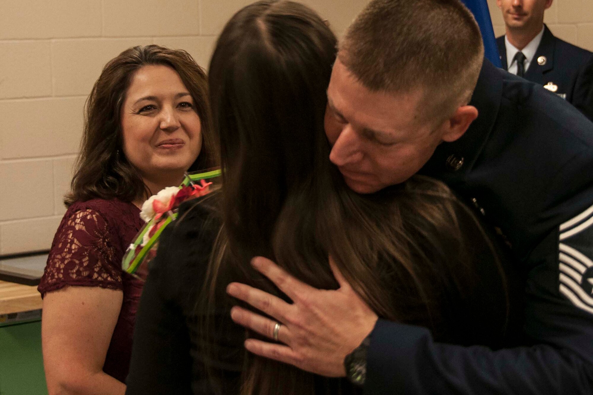U.S. Air Force Master Sgt. Robert Carpenter gives his daughter, Kayla, a hug during his retirement ceremony while his wife, Cassandra looks on at Barksdale Air Force Base, La., Oct. 15, 2016.   Carpenter had just presented his wife and daughter with flowers in thanksgiving for their support during his 22-year military career.   His other daughter, Hailey, could not attend as she is in training with the U.S. Air Force at Ft. Lee, Va.   Both of Carpenter's daughters were born while he was on active duty.  (U.S. Air Force photo by Tech. Sgt. Ted Daigle/released).    