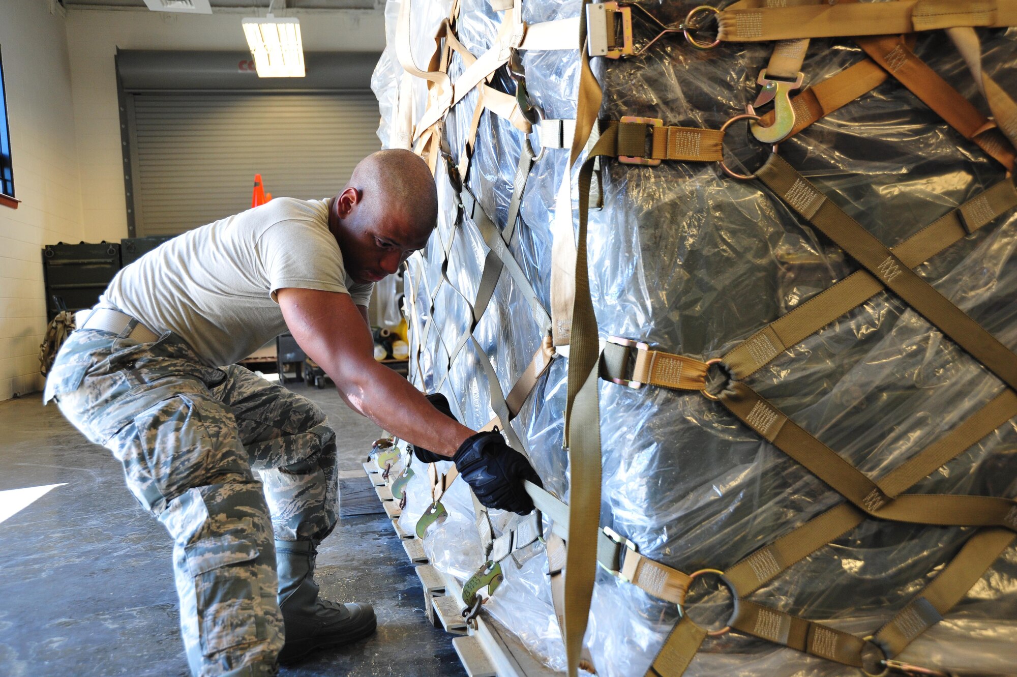 Staff Sgt. Mychal Hutchinson, 41st Aerial Port Squadron air transportation specialist, tightens the straps on the cargo net during the pallet buildup event. The members competed in teams in the Port Dawg Challenge in five events: forklift driving, Jeopardy, the chains and devices tie-down, pallet buildup and a fit-to fight challenge.  (U.S. Air Force Photo / Master Sgt. Jessica Kendziorek)