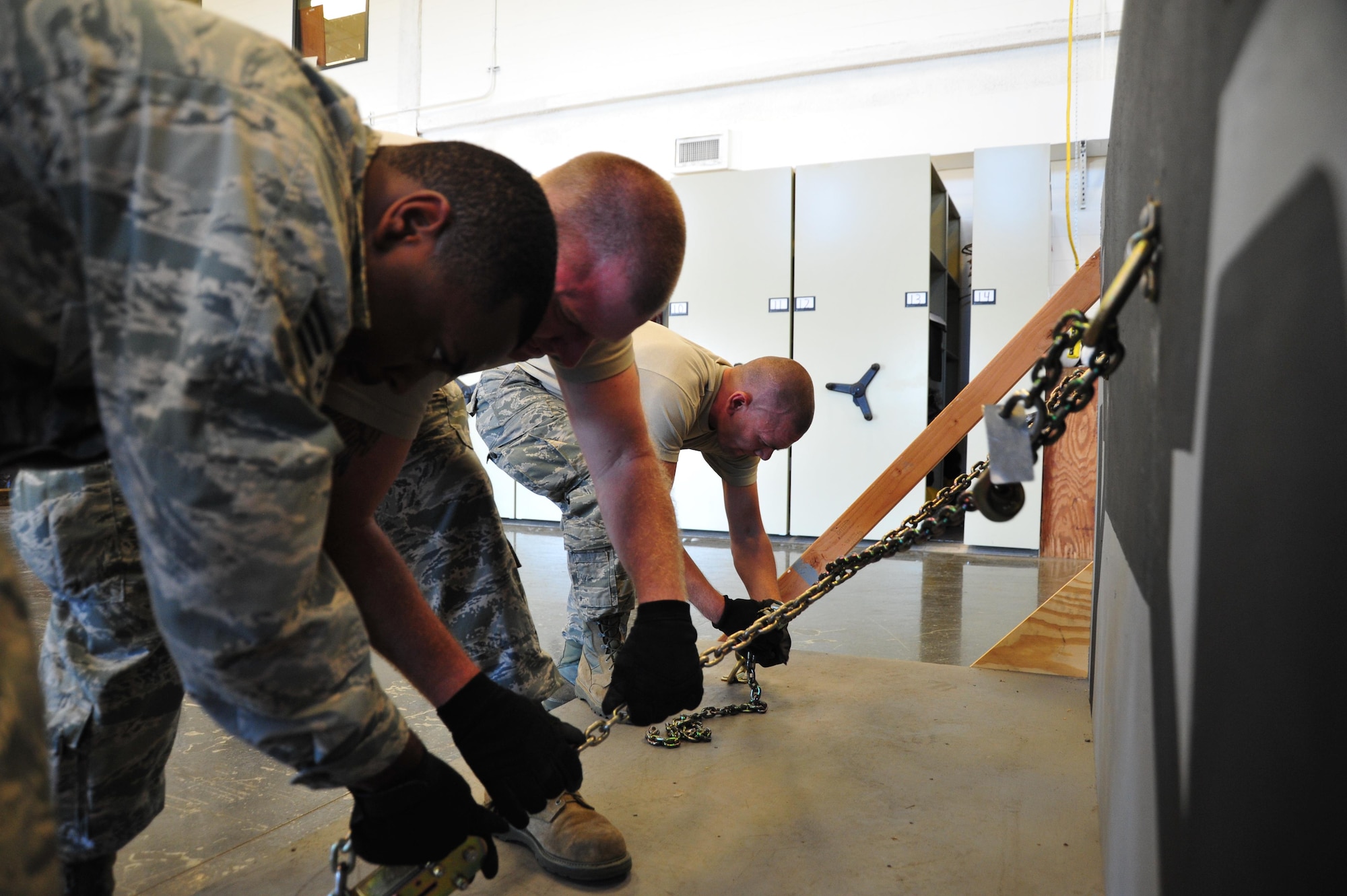 Staff Sgt. Mychal Hutchinson, 41st Aerial Port Squadron air transportation specialist, tightens the straps on the cargo net during the pallet buildup event. The members competed in teams in the Port Dawg Challenge in five events: forklift driving, Jeopardy, the chains and devices tie-down, pallet buildup and a fit-to fight challenge.  (U.S. Air Force Photo / Master Sgt. Jessica Kendziorek)