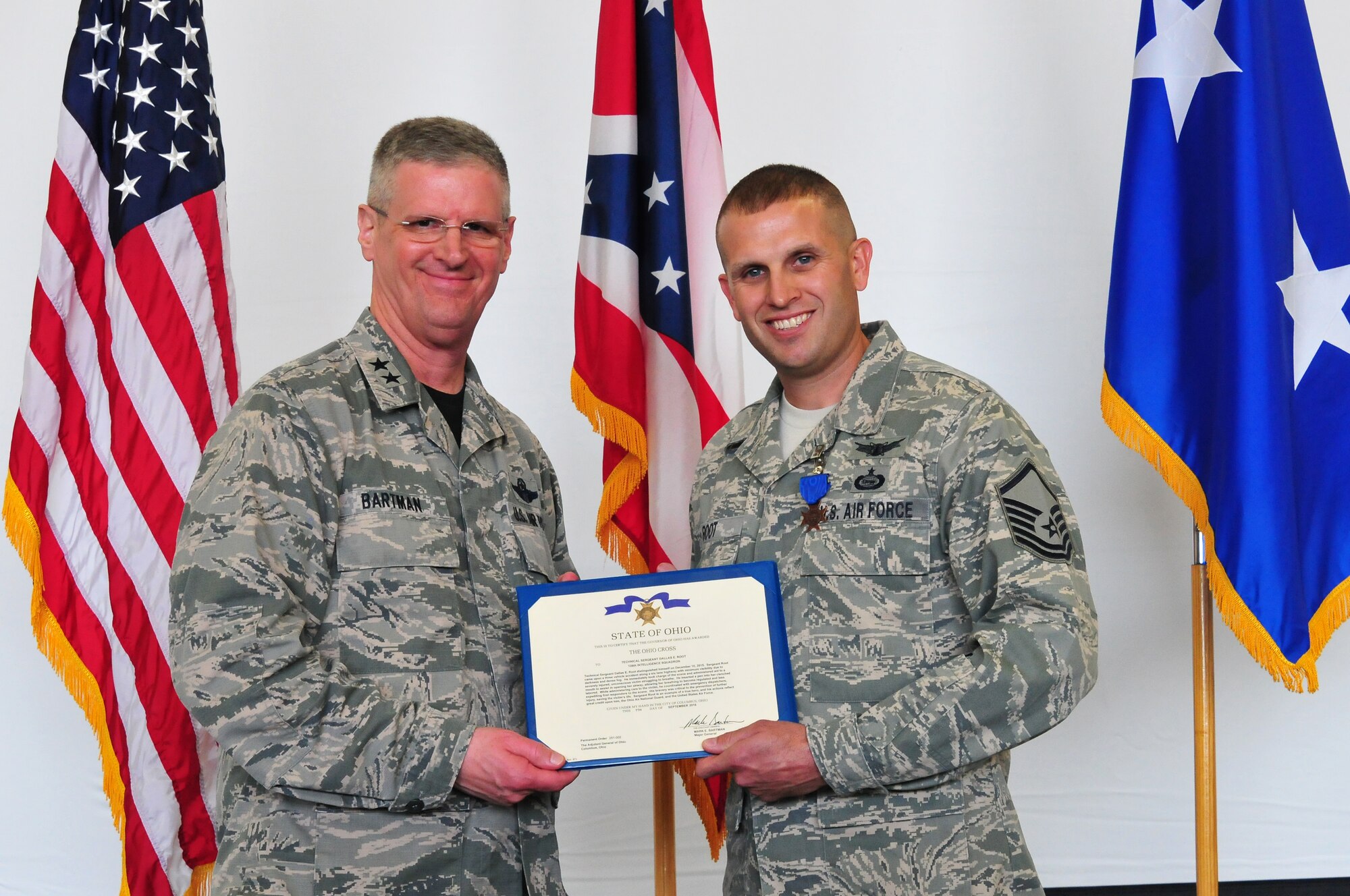 Master Sgt. Dallas Root, a member of the 178th Wing, receives the Ohio Cross award presented by the Ohio Adjutant General, Maj. Gen. Mark Bartman at Springfield Air National Guard Base in Springfield, Ohio, Oct. 15, 2016. Root received the award for administering aid to a vehicle accident victim, and coordinating with emergency dispatchers. Ten years ago, Root received his first Ohio Cross for diving into a freezing pond to save a vehicle accident victim. (U.S. Air National Guard photo by Rachel Simones)