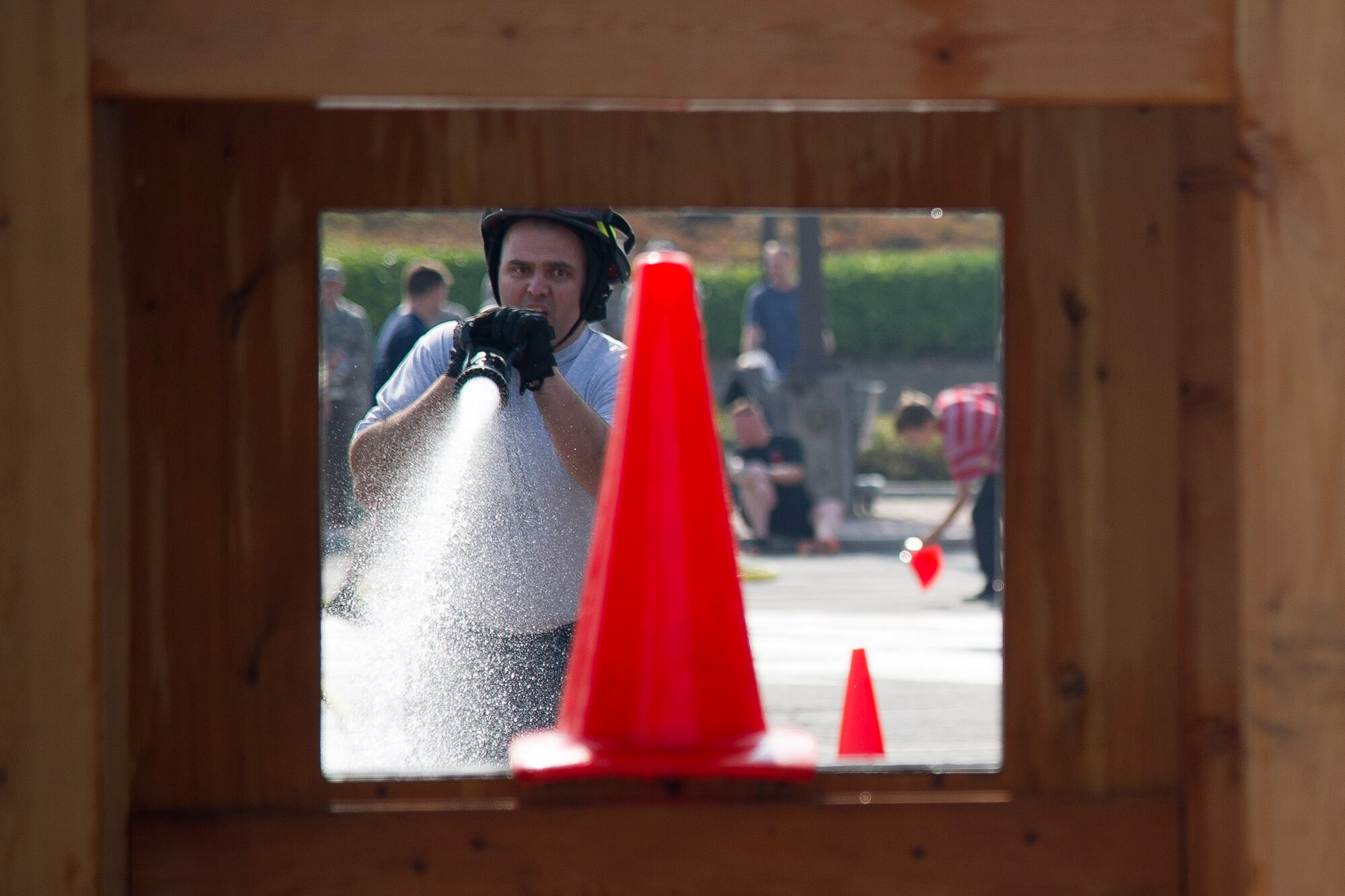 U.S. Air Force Maj. Jeffery Hughes, 51st Civil Engineer Squadron deputy commander, attempts to shoot down a cone with a firefighting hose during Fire Muster 2016 on Osan Air Base, Republic of Korea, Oct. 13, 2016.  Osan’s firefighters organized the fire muster to bring awareness to Osan for Fire Prevention Week Oct. 9-15.  The fire muster put together teams of four in a relay race with teams competing in a variety of firefighting skills. (U.S. Air Force photo by Staff Sgt. Jonathan Steffen) 