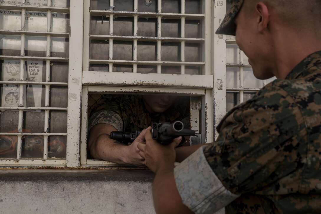 Cpl. Chris Sagan receives a M16A4 service rifle for inspection from Lance Cpl. Brandon Fierro after he conducted weapon’s maintenance at the III Marine Expeditionary Force Headquarters Group Armory on Camp Hansen, Okinawa, Japan, October 12, 2016.  As a non-commissioned officer, Sagan’s job at the armory is to supervise his junior Marines as well as help with maintenance and repairs to the weapons. Sagan, from Dalton, Pennsylvania, is a small arms repair technician for III MHG, III MEF. (U.S. Marine Corps photo by Cpl. Jessica Etheridge / Released)