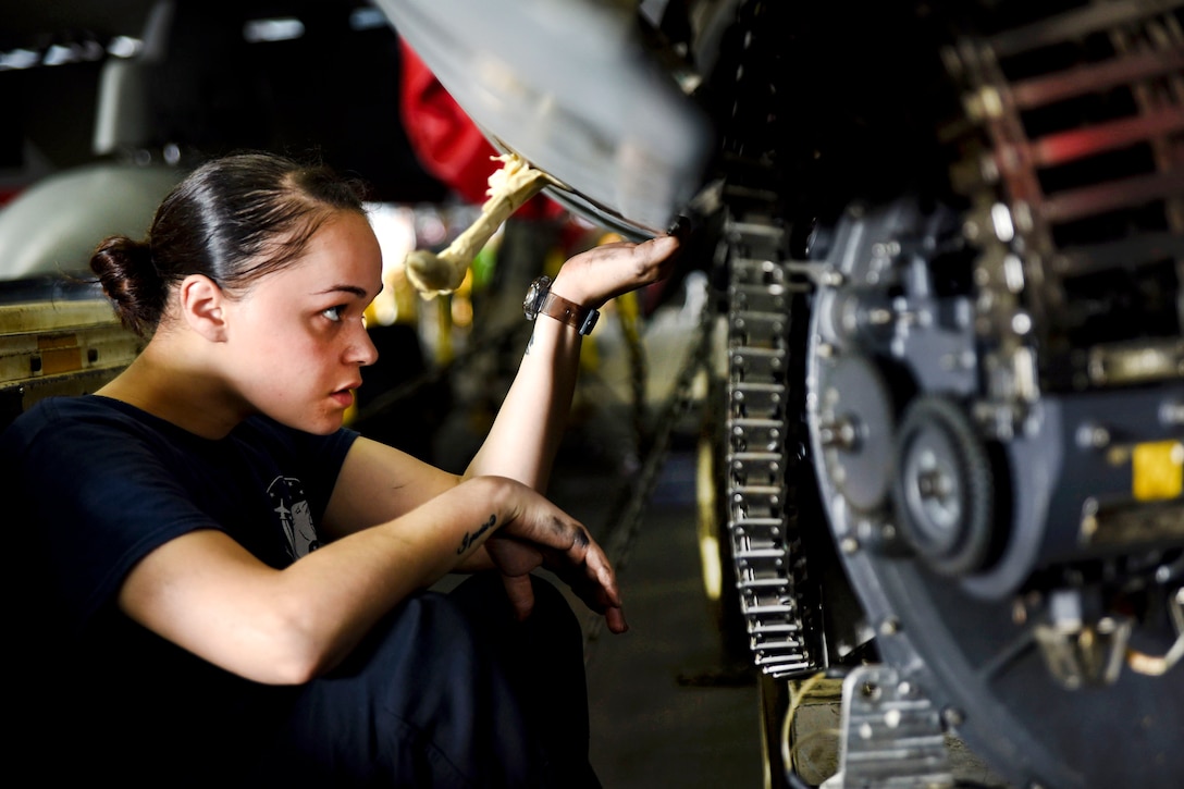 Navy Seaman Oriana Rosario holds a panel in place during routine 84-day maintenance on an F/A-18C Hornet aircraft assigned to Strike Fighter Squadron 131 in the hangar bay of the aircraft carrier USS Dwight D. Eisenhower in the Persian Gulf, Oct. 14, 2016. Rosario is an aviation ordnanceman. Navy photo by Seaman Christopher A. Michaels