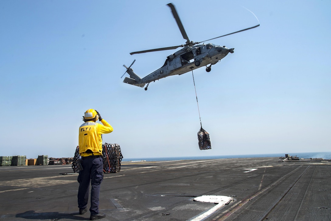 Navy Petty Officer 1st Class Derek Welch directs an MH-60S Sea Hawk helicopter assigned to Helicopter Sea Combat Squadron 7 as it unloads cargo on the flight deck of the aircraft carrier USS Dwight D. Eisenhower during a replenishment-at-sea with the fleet replenishment oiler USNS Pecos in the Persian Gulf, Oct. 14, 2016. Welch is an aviation boatswain's mate (handling). Navy photo by Petty Officer 3rd Class Robert J. Baldock 