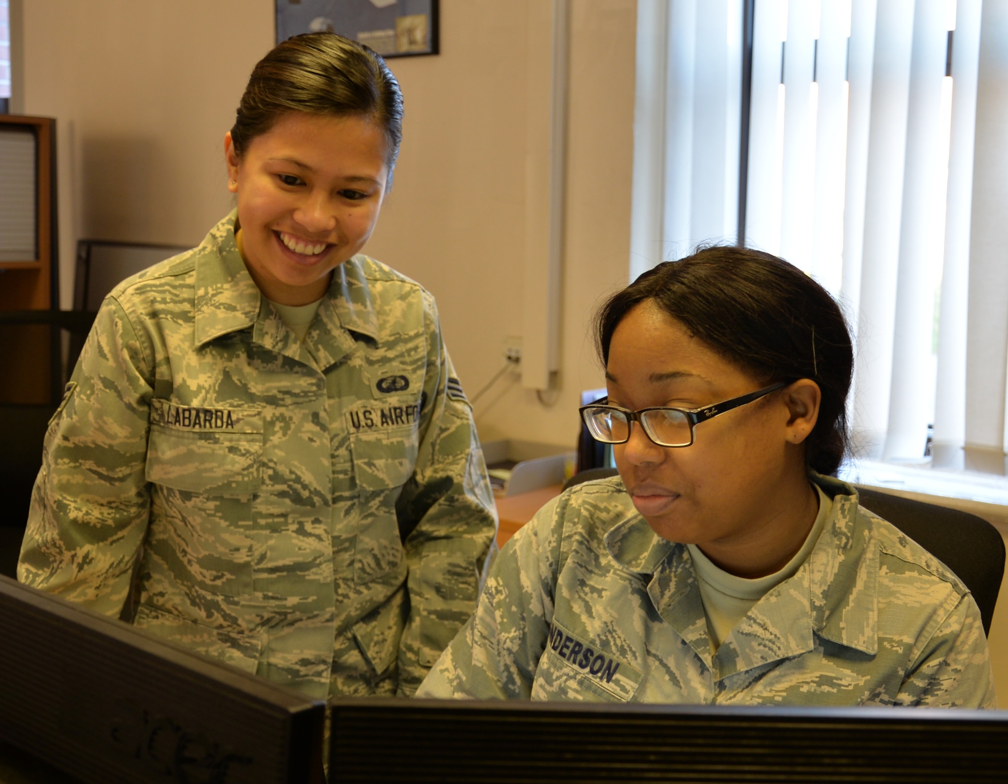 U.S. Air Force Senior Airman Regine Labarda, left, 100th Comptroller Squadron relocation technician, and U.S. Air Force Staff Sgt. Michelle Anderson, 100th CPTS relocations supervisor, discuss an upcoming meeting Oct. 5, 2016, on RAF Mildenhall, England. Labarda helps new military members in-process and file their travel vouchers. (U.S. Air Force photo by Gina Randall)