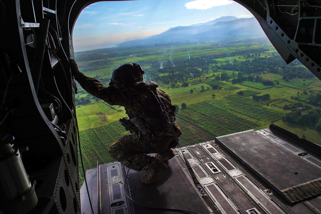 Army Staff Sgt. Jim Burley looka out the back of a CH-47 Chinook for clearance during a relief mission in Port-au-Prince, Haiti, Oct. 14, 2016. Burley is a crew chief assigned to 1st Battalion, 228th Aviation Regiment. Air Force photo by Staff Sgt. Paul Labbe
