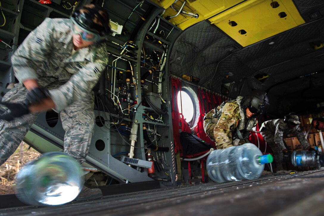 Troops roll large water bottles down the ramp of a CH-47 Chinook helicopter during a relief mission in Anse d'Hainault, Haiti, Oct. 14, 2016. Air Force photo by Staff Sgt. Paul Labbe