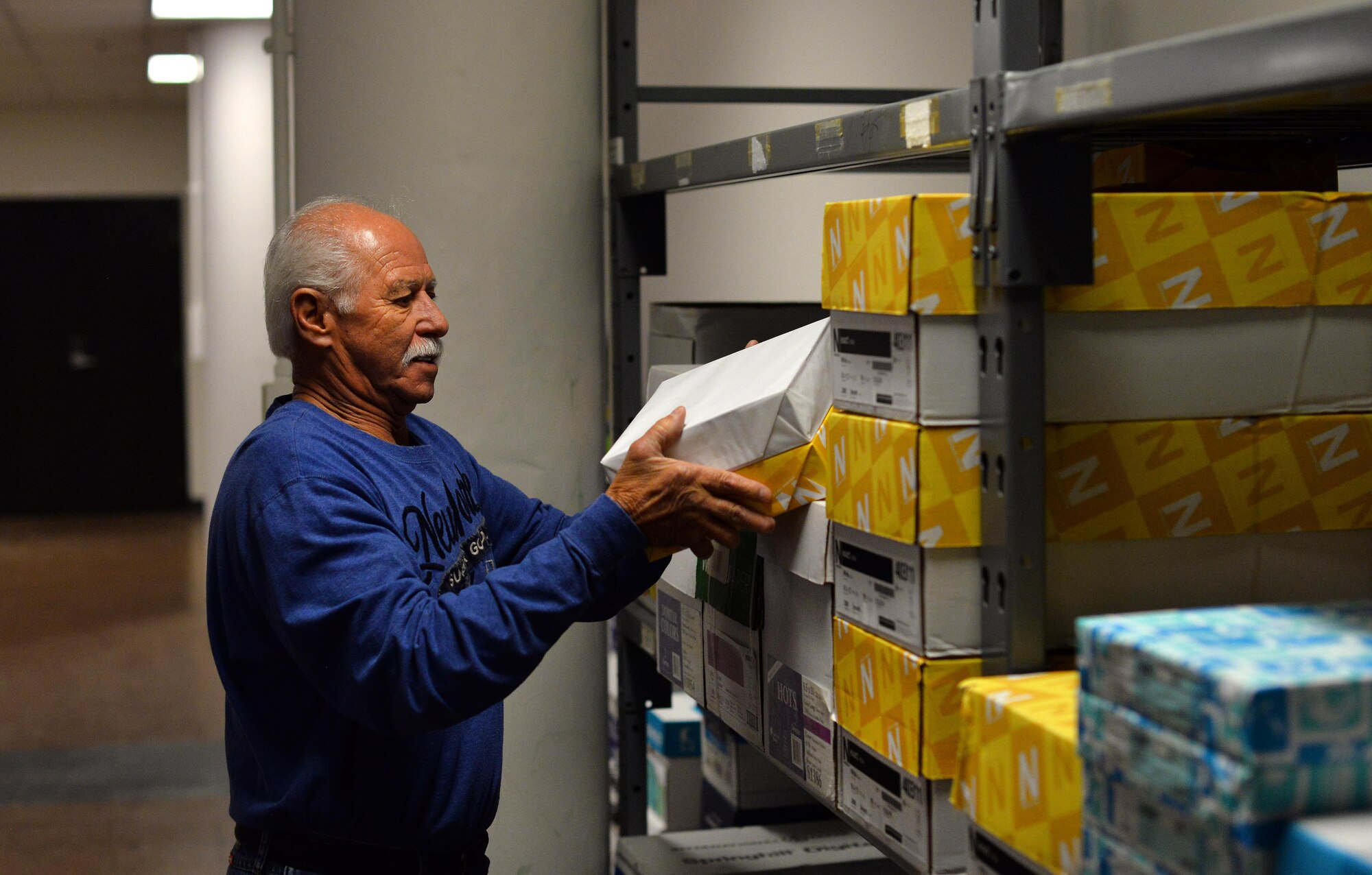 Joe Knott, an electronic duplicating systems technician with Defense Logistic Agencies Document Services, walks through an assortment of papers inside the supply room of the print shop located in the Martin Bomber building on Oct. 11, Offutt Air Force Base, Neb.  The Document Services print shop offers a wide variety of paper weights and finishes for their Department of Defense customers to choose from.  