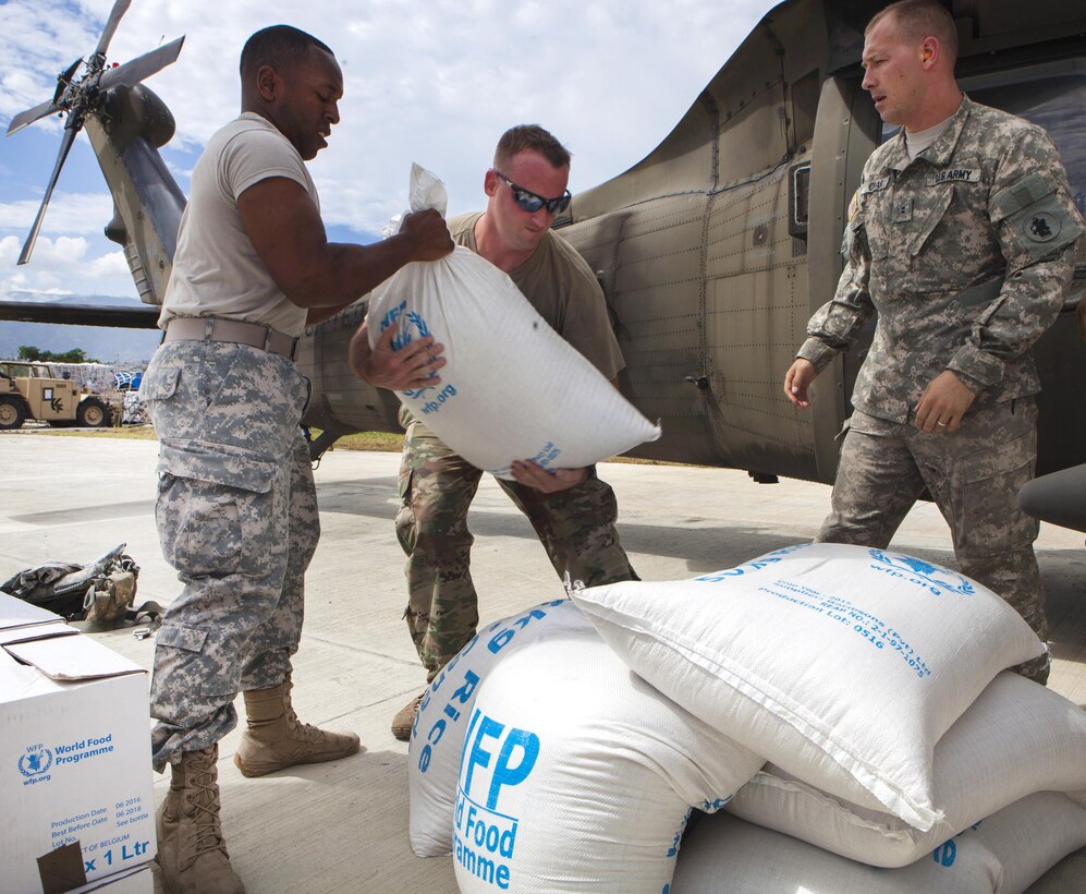 Army Sgt. Denoval D. Reed II, left, passes bags of rice to Army Sgt. Jonathan Boni, center, as Army Warrant Officer II Craig waits to load them onto a UH-60 Black Hawk helicopter in Port-au-Prince, Haiti, Oct. 14, 2016, for delivery to  areas Hurricane Matthew hit. Reed, a petroleum laboratory specialist, Boni, a signal support systems specialist, and Craig, a pilot, are assigned to Joint Task Force Matthew. The U.S. Southern Command directs the team, which includes Marines, soldiers and sailors. Marine Corps photo by Sgt. Adwin Esters