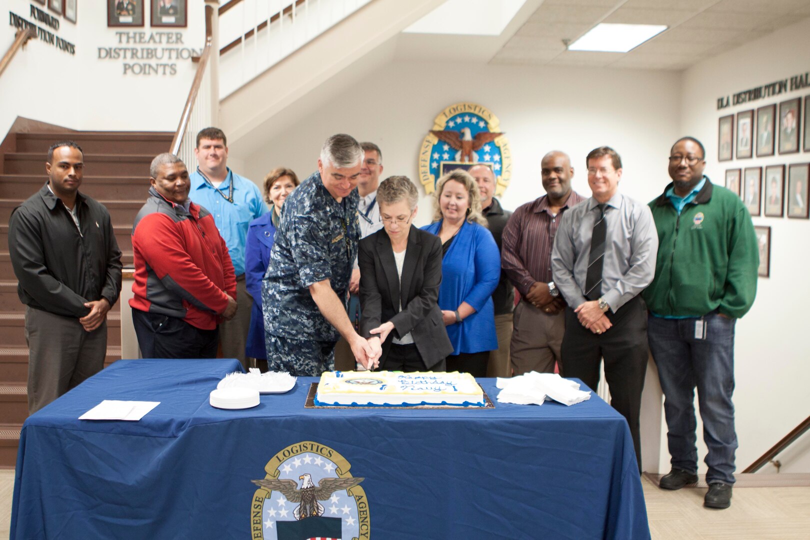 DLA Distribution deputy commander Twila Gonzales, Senior Executive Service, center, cuts a cake honoring the Navy’s 241st birthday alongside DLA Distribution’s active, reserve and retired Navy sailors.  