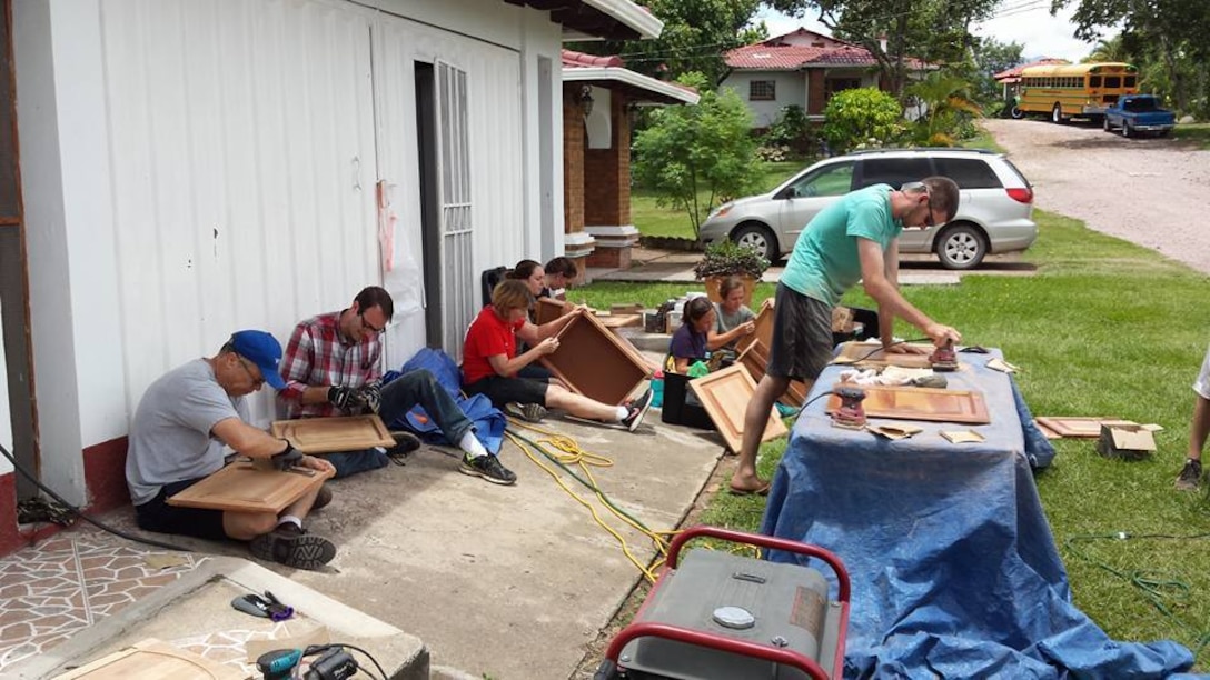 Pfc. Joshua Anderson, (green t-shirt) a service desk technician at the 335th Signal Command (Theater) headquarters, and a native of Woodstock, Georgia, sands cabinet doors during a recent refurbishing project in Siguatepeque, Honduras.  Anderson was part of a group of volunteers who hosted English classes for children and did various refurbishing and beautification projects at a seminary there.