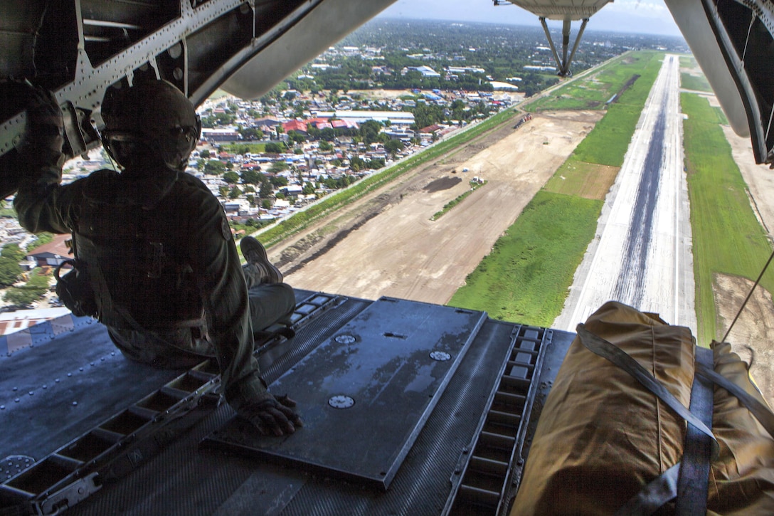 Marine Corps Staff Sgt. Adam Stanley rides on the rear ramp of a CH-53E Super Stallion helicopter during takeoff from Port-au-Prince International Airport, Haiti, Oct. 15, 2016, to deliver goods to areas affected by Hurricane Matthew. Stanley is a crew chief assigned to Joint Task Force Matthew, a U.S. Southern Command-directed team that includes Marines, soldiers, sailors and airmen. It is providing critical airlift capabilities during the initial stages of the U.S. Agency for International Development's disaster relief operations in Haiti while the international response builds. Marine Corps photo by Sgt. Adwin Esters