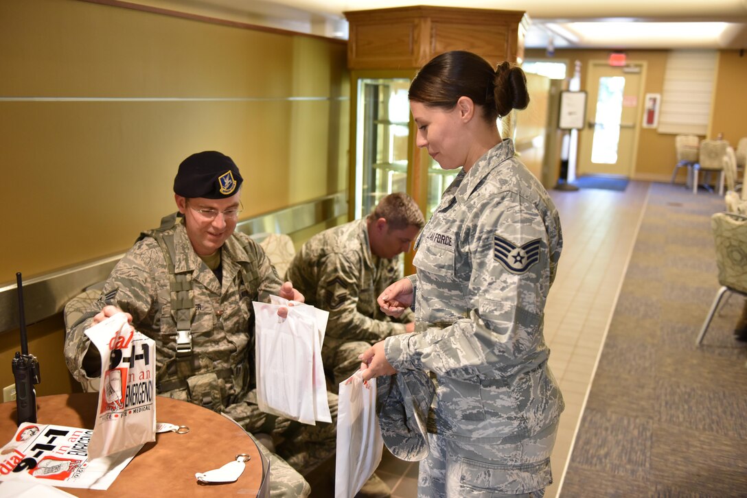 Staff Sgt. Randal Levander, security response team leader with the 911th Security Forces Squadron, passes out bags to Airmen with information about how to not become victim to a crime at the Pittsburgh International Airport Air Reserve Station, Pa., Oct. 15, 2016. The table, set up by 911 SFS, was organized to draw attention to Crime Awareness Month and the steps Airmen can take to prevent crimes. (U.S. Air Force photo by Staff Sgt. Marjorie A. Bowlden)