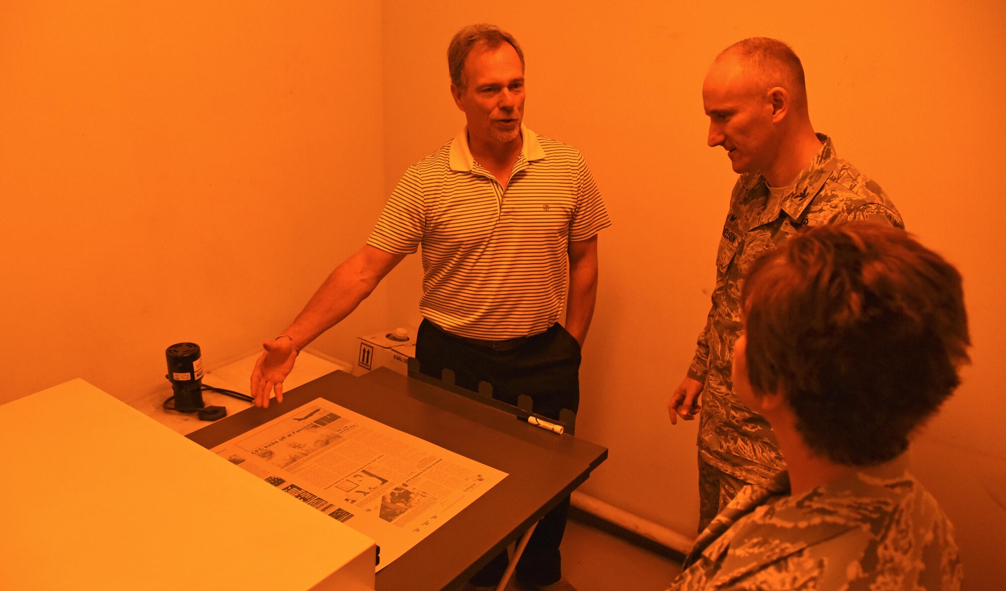 Harlan Shellabarger, Cheney Free Press publisher, shows Col. Ryan Samuelson, 92nd Air Refueling Wing commander, and Chief Master Sgt. Shannon Rix, 92nd ARW command chief, the inside of the CFP dark room Oct. 13, 2016, at Cheney. The dark room is essential to creating the printing plates for the Fairchild Flyer. Each plate is produced to apply a designated color to the newsprint: black, cyan, magenta or yellow. (U.S. Air Force photo/Senior Airman Mackenzie Richardson)