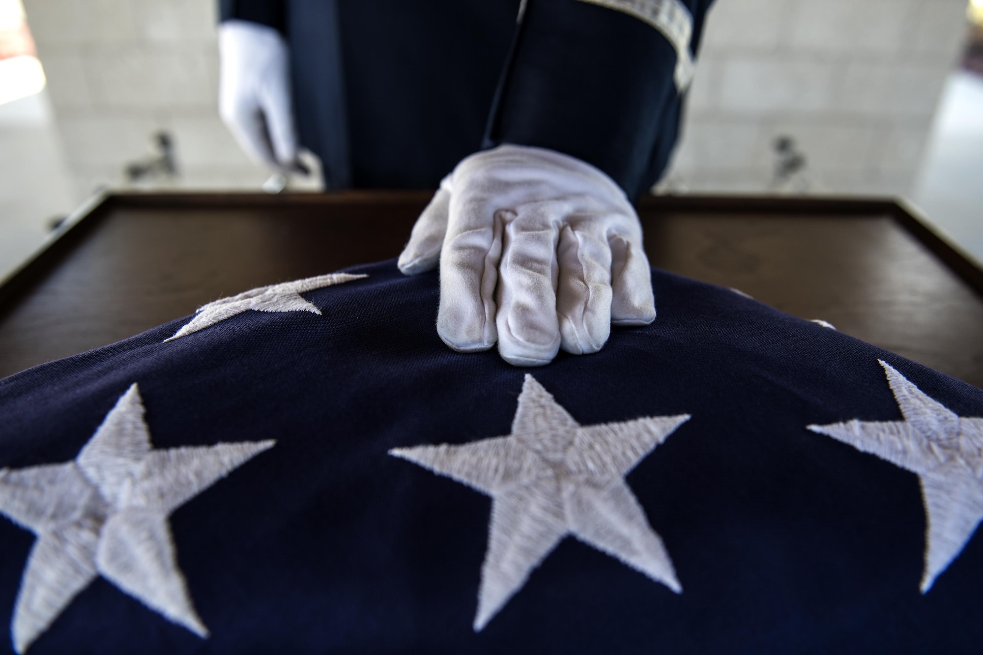 A member of the Moody Air Force Base Honor Guard places a hand on a folded United States flag before a funeral, Oct. 13, 2016, in Jacksonville, Fla. Moody’s honor guard performs congressionally mandated honors throughout 51 counties within Southern Georgia and Northern Florida. (U.S. Air Force photo by Airman 1st Class Janiqua P. Robinson)